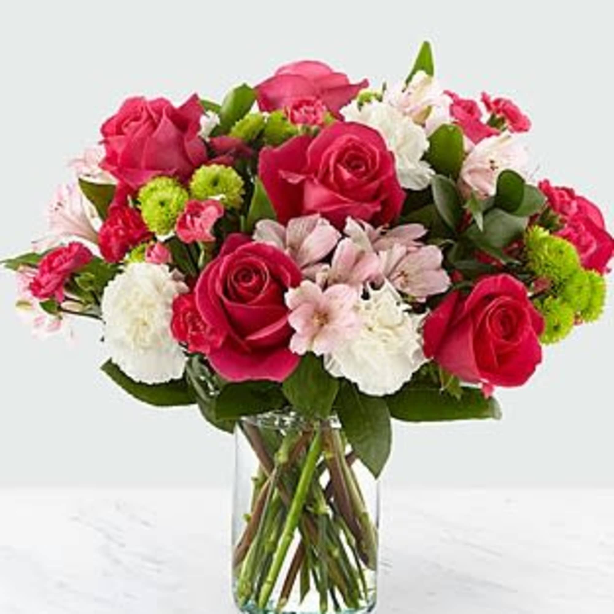 Bouquet of pink roses and mixed flowers in a clear glass vase