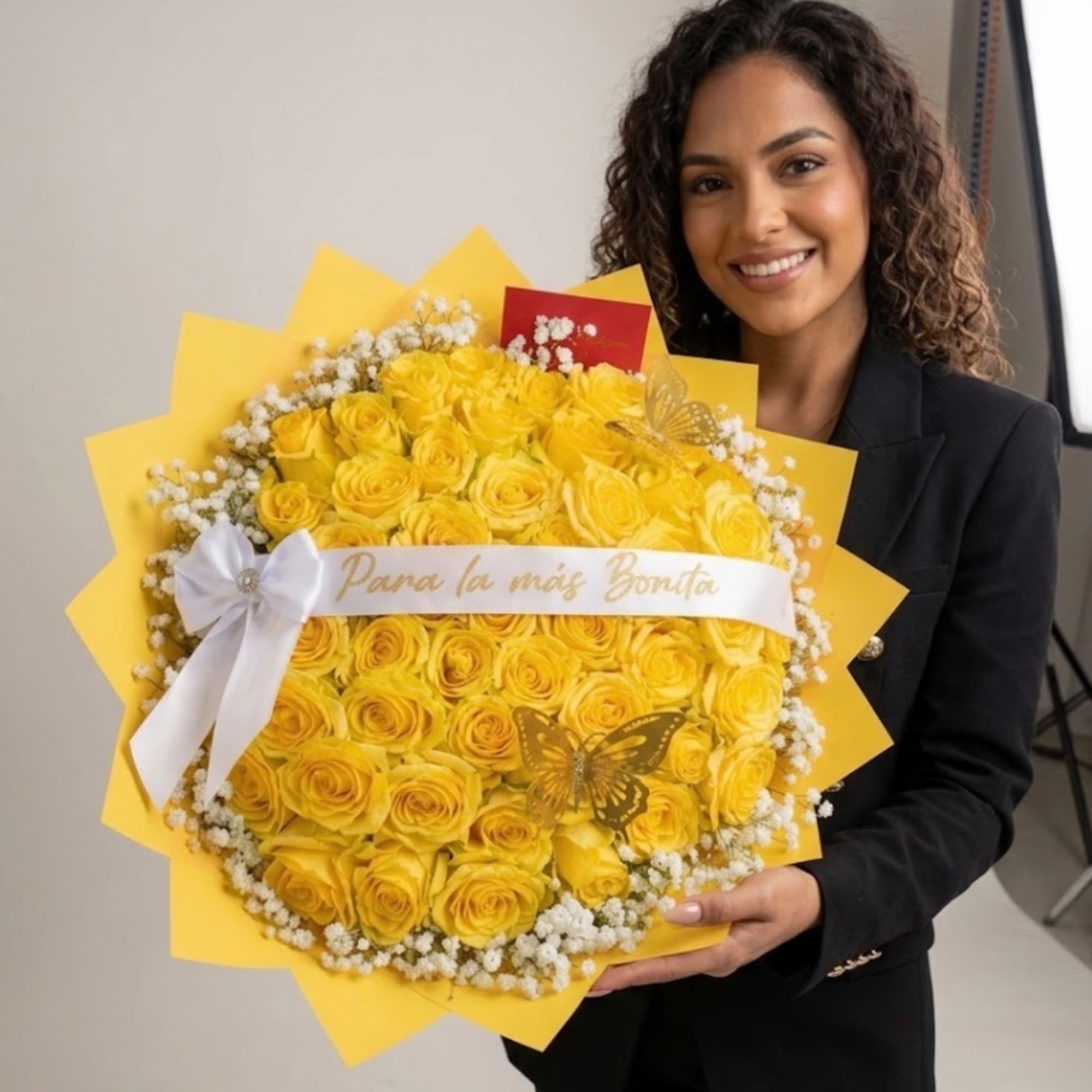 Woman holding a large bouquet of yellow roses with a white ribbon