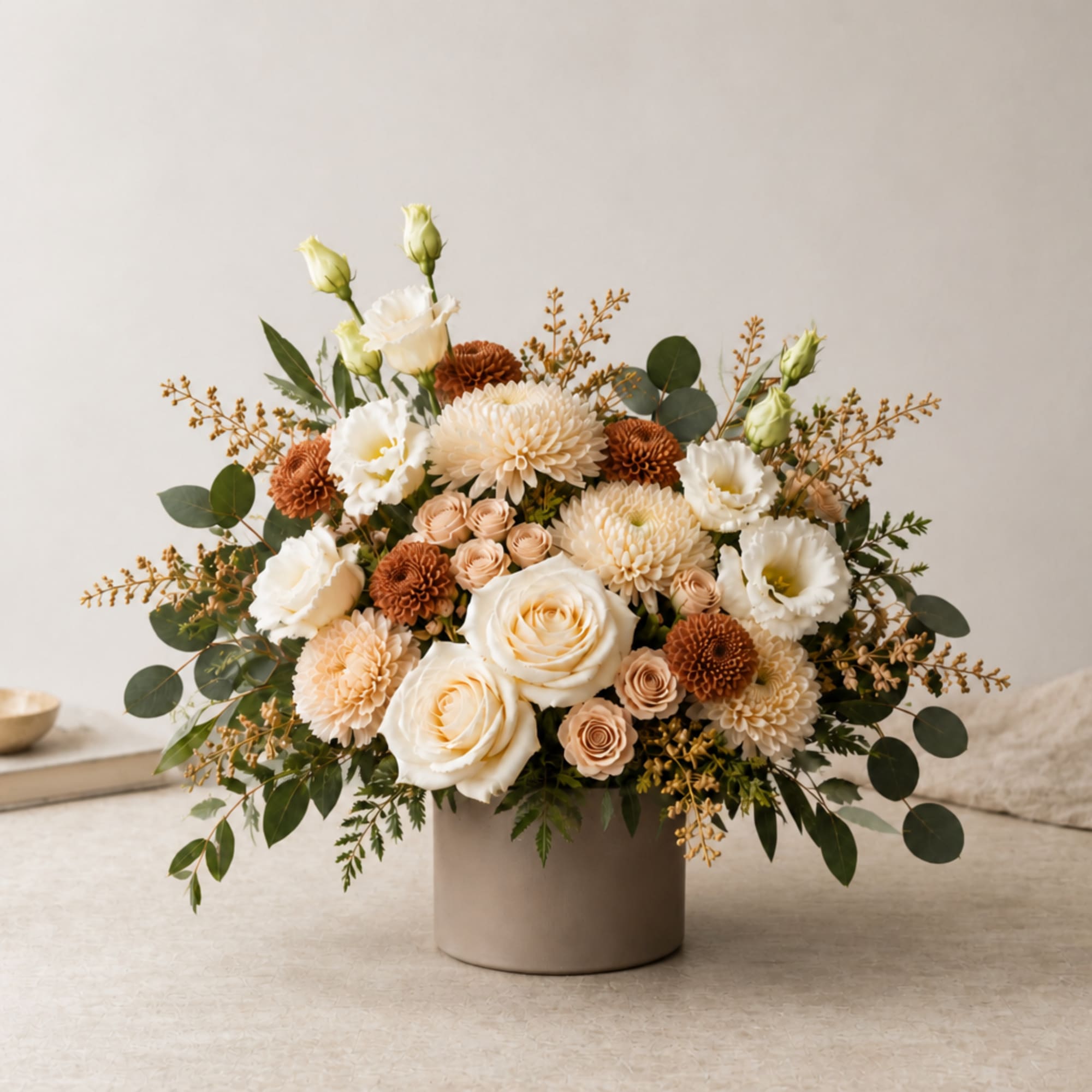 Cream and peach floral arrangement in a beige vase