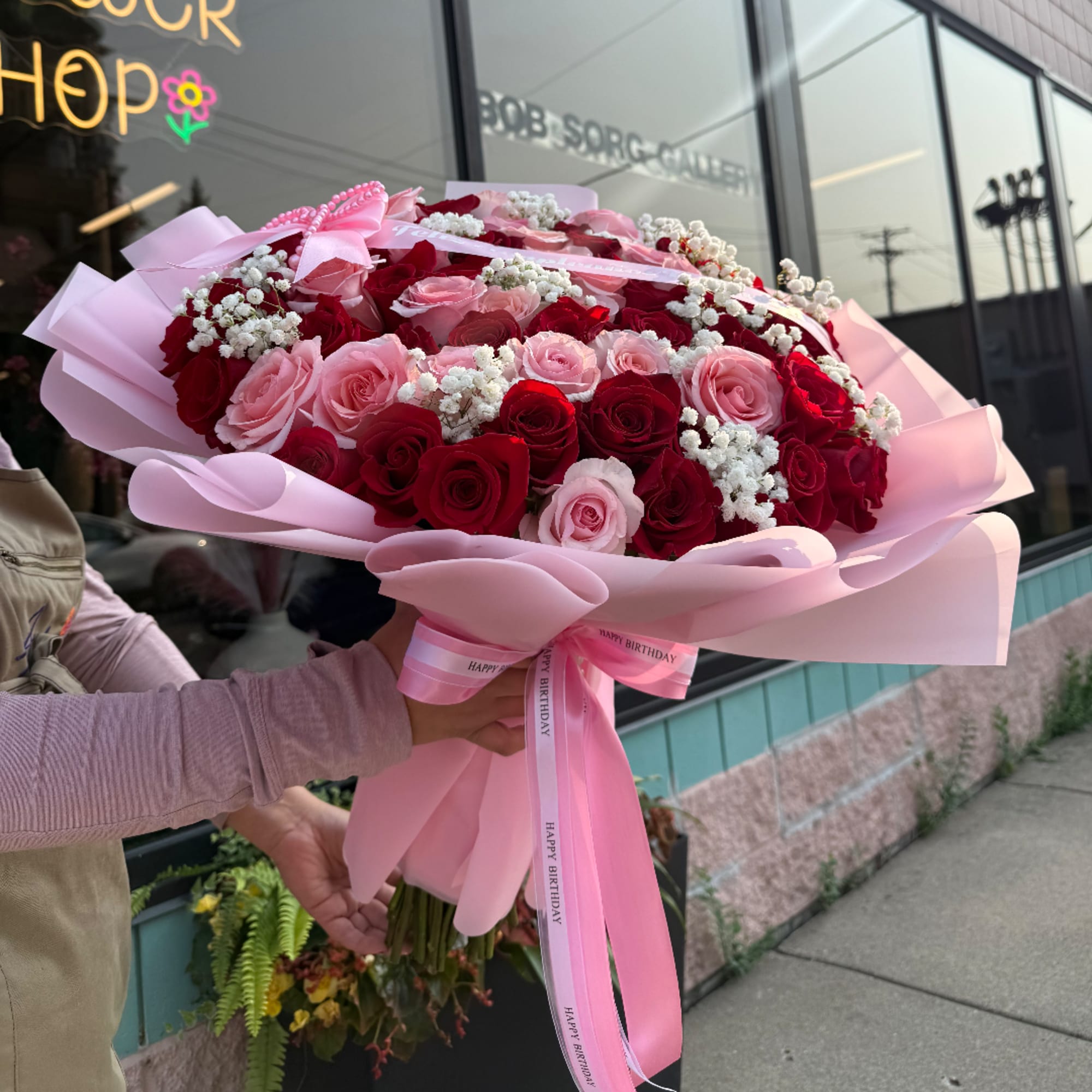 Large bouquet of red and pink roses wrapped in pale pink paper