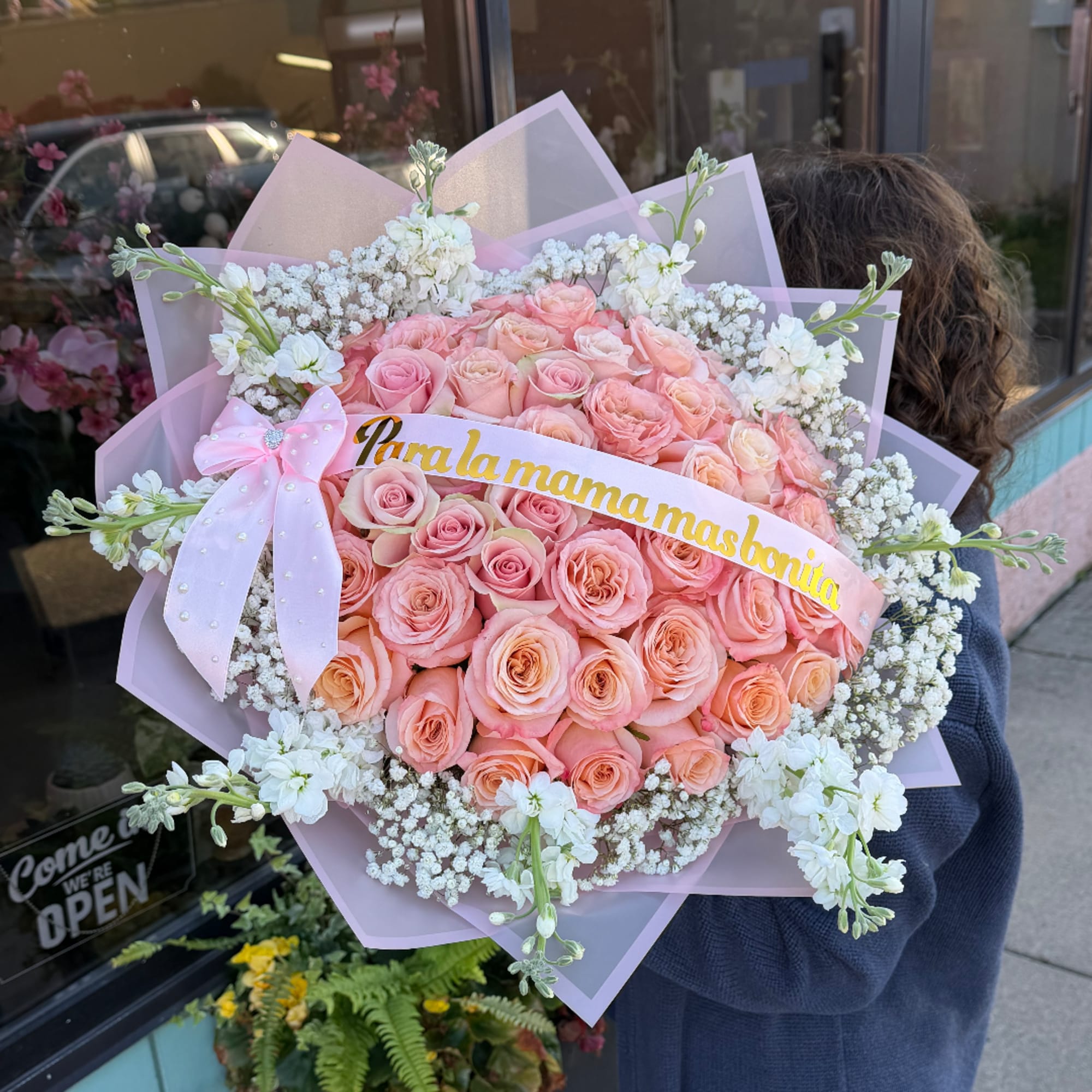 Large bouquet of pink roses with white filler flowers and a pink ribbon