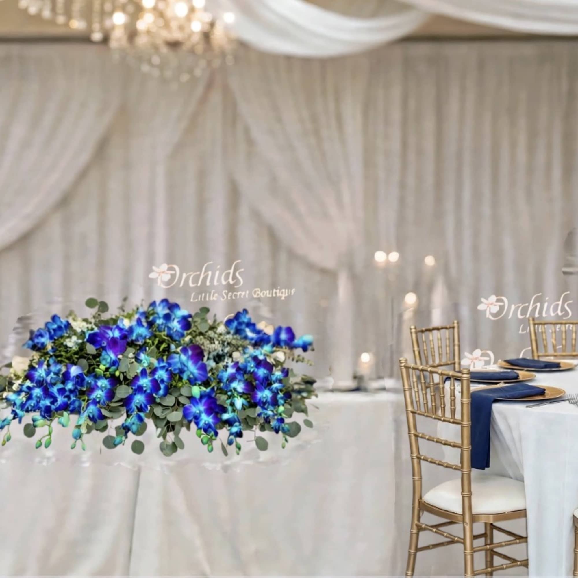 Blue floral wedding centerpieces on draped tables with gold chairs