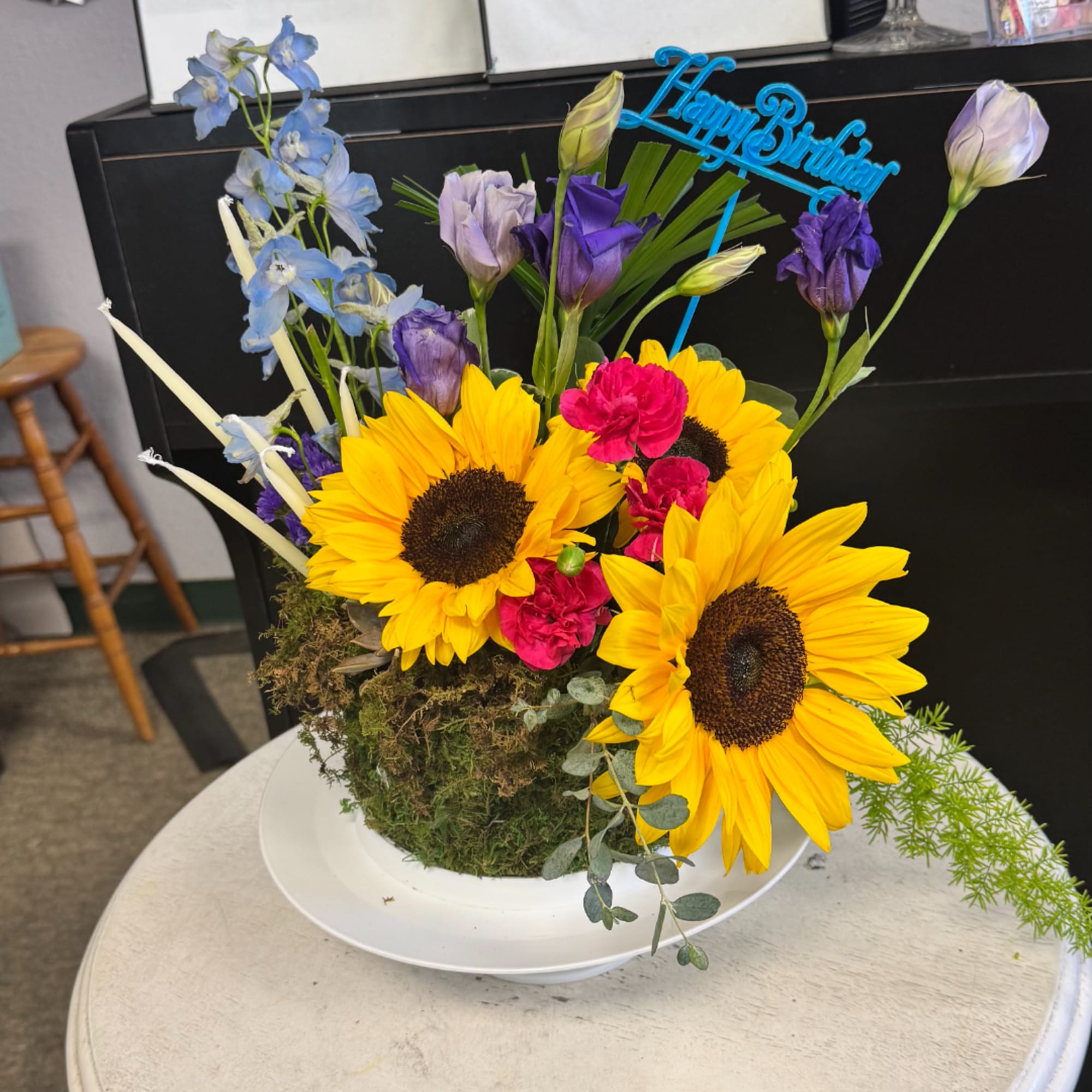 Bright sunflower and mixed flower arrangement in a white bowl