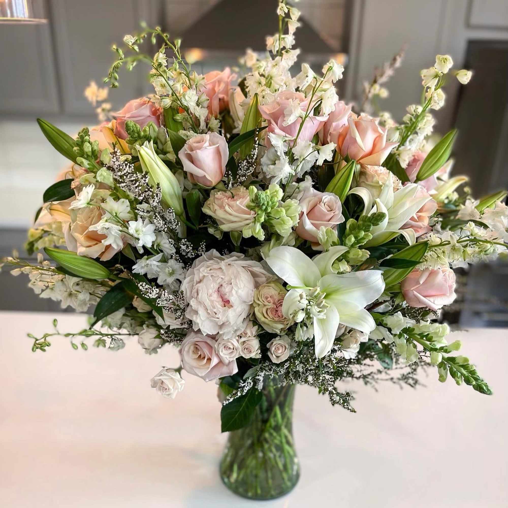 Large pastel bouquet of roses and lilies in a glass vase