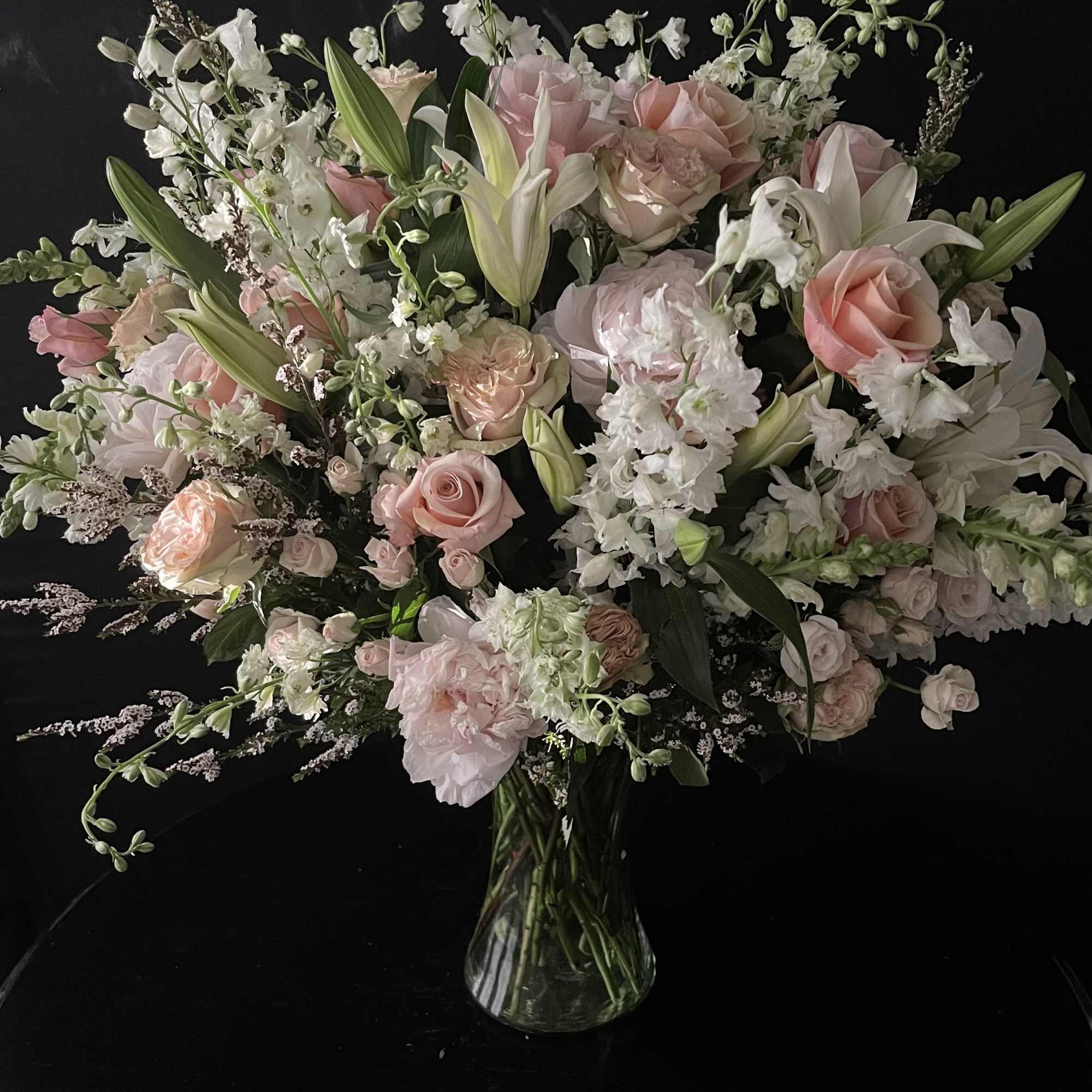 Large bouquet of pale pink and white flowers in a clear glass vase