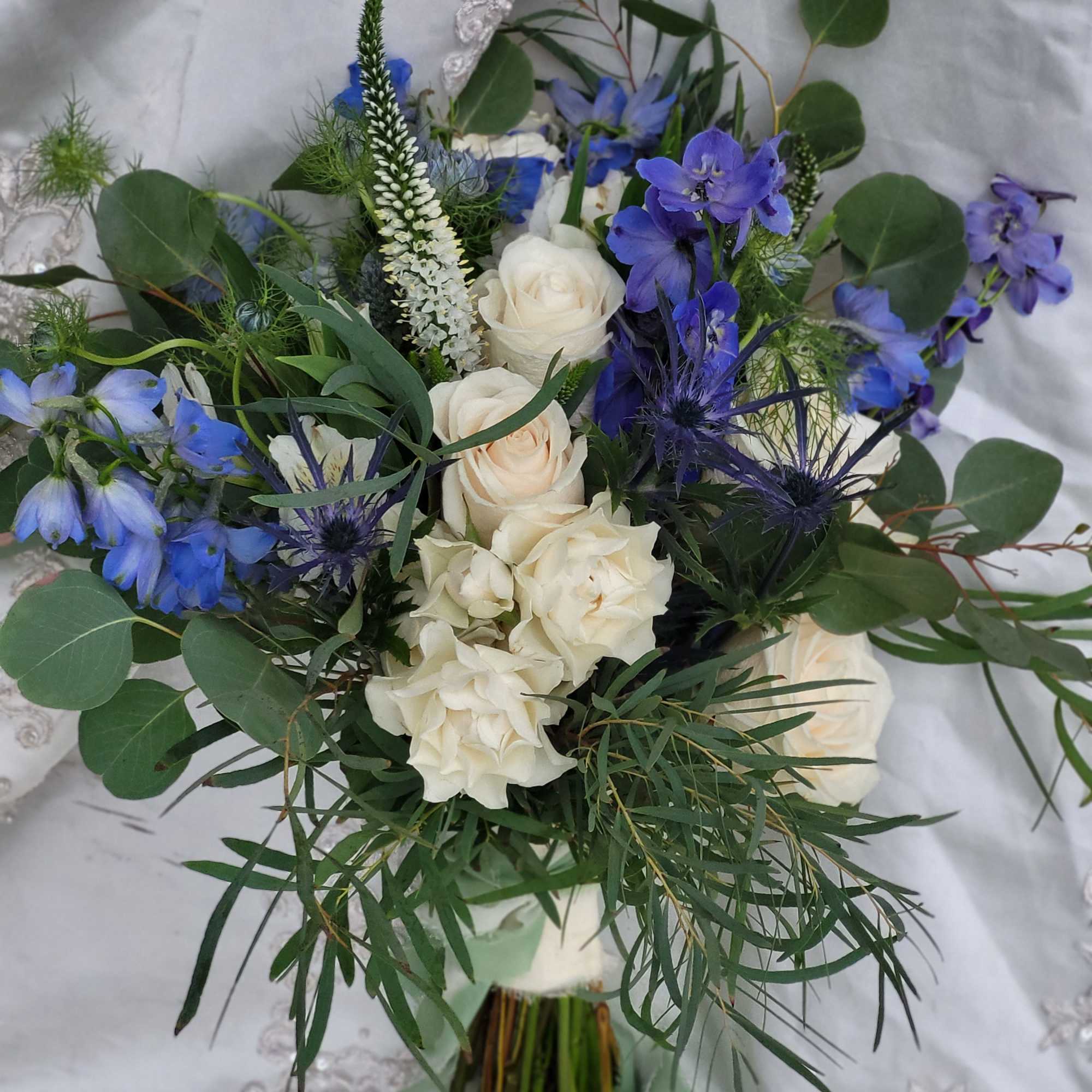 Bouquet of white roses and blue flowers with greenery