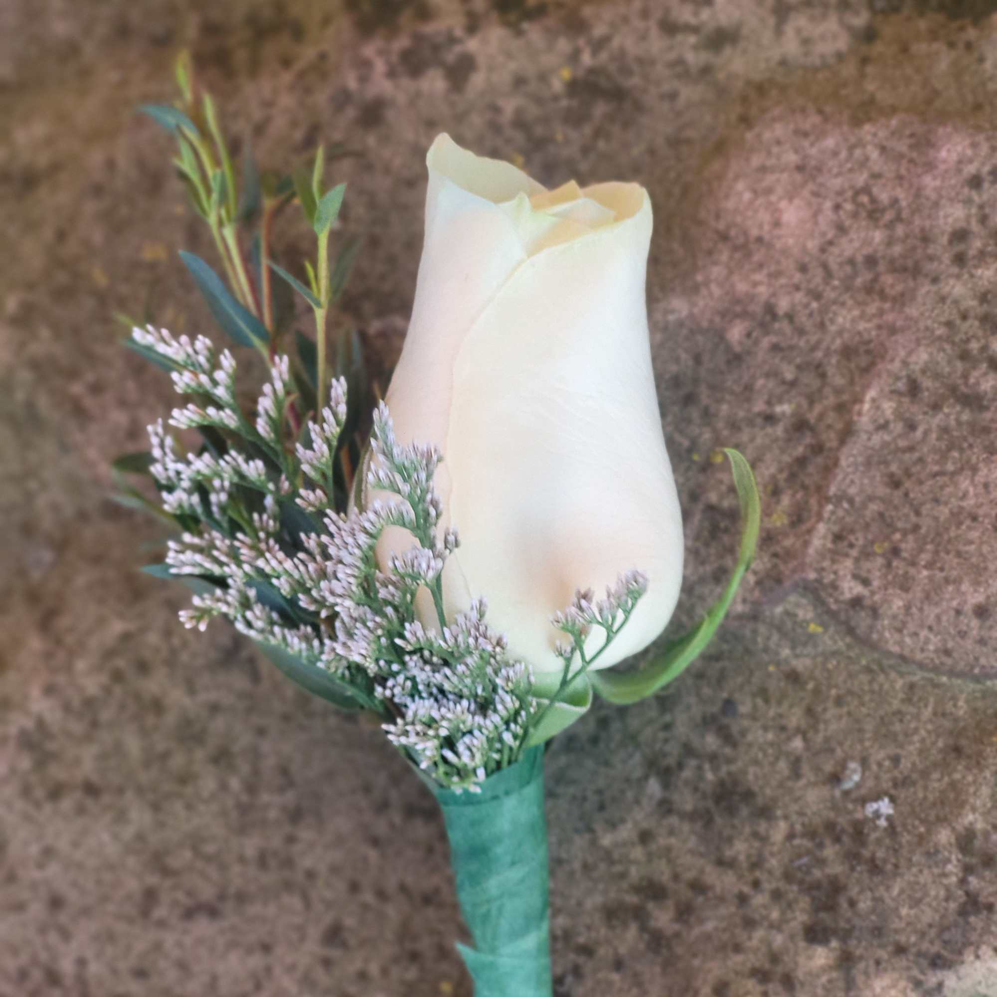 Single white rose boutonniere with small lavender filler flowers