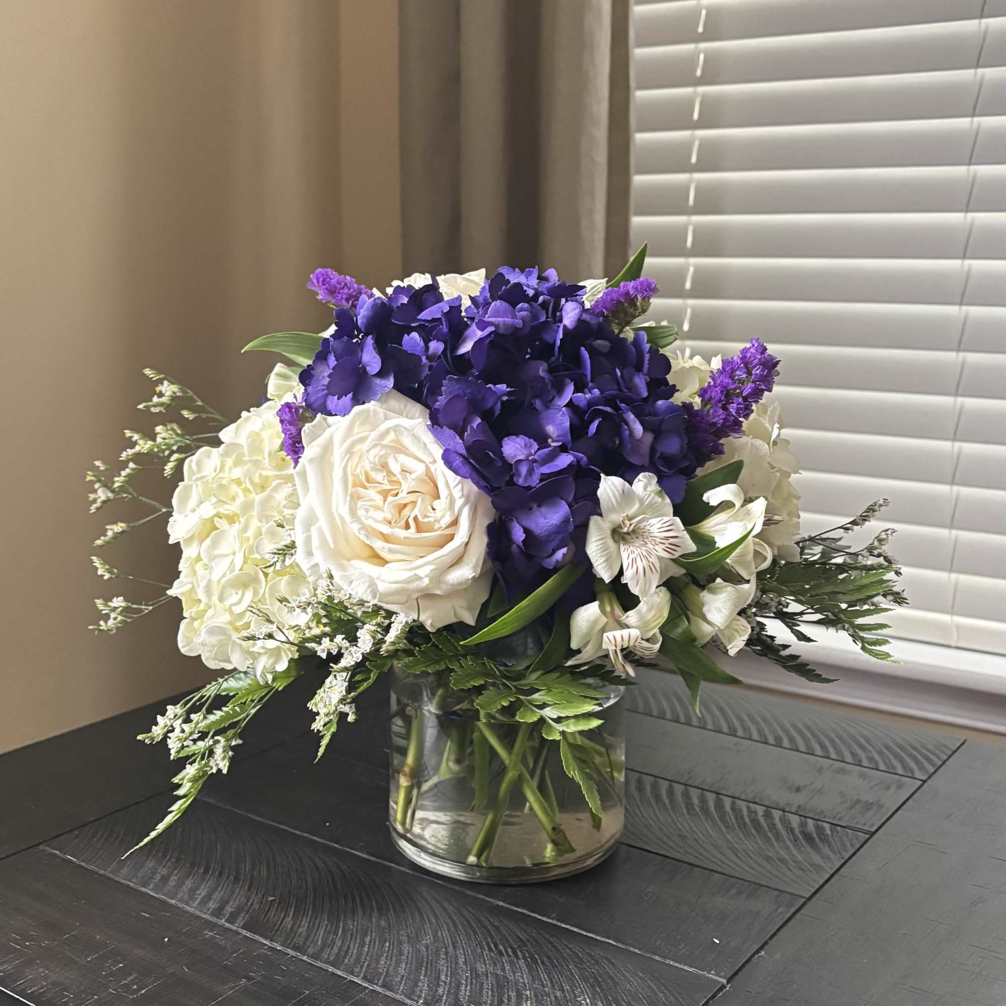 Purple and white floral arrangement in a clear glass vase