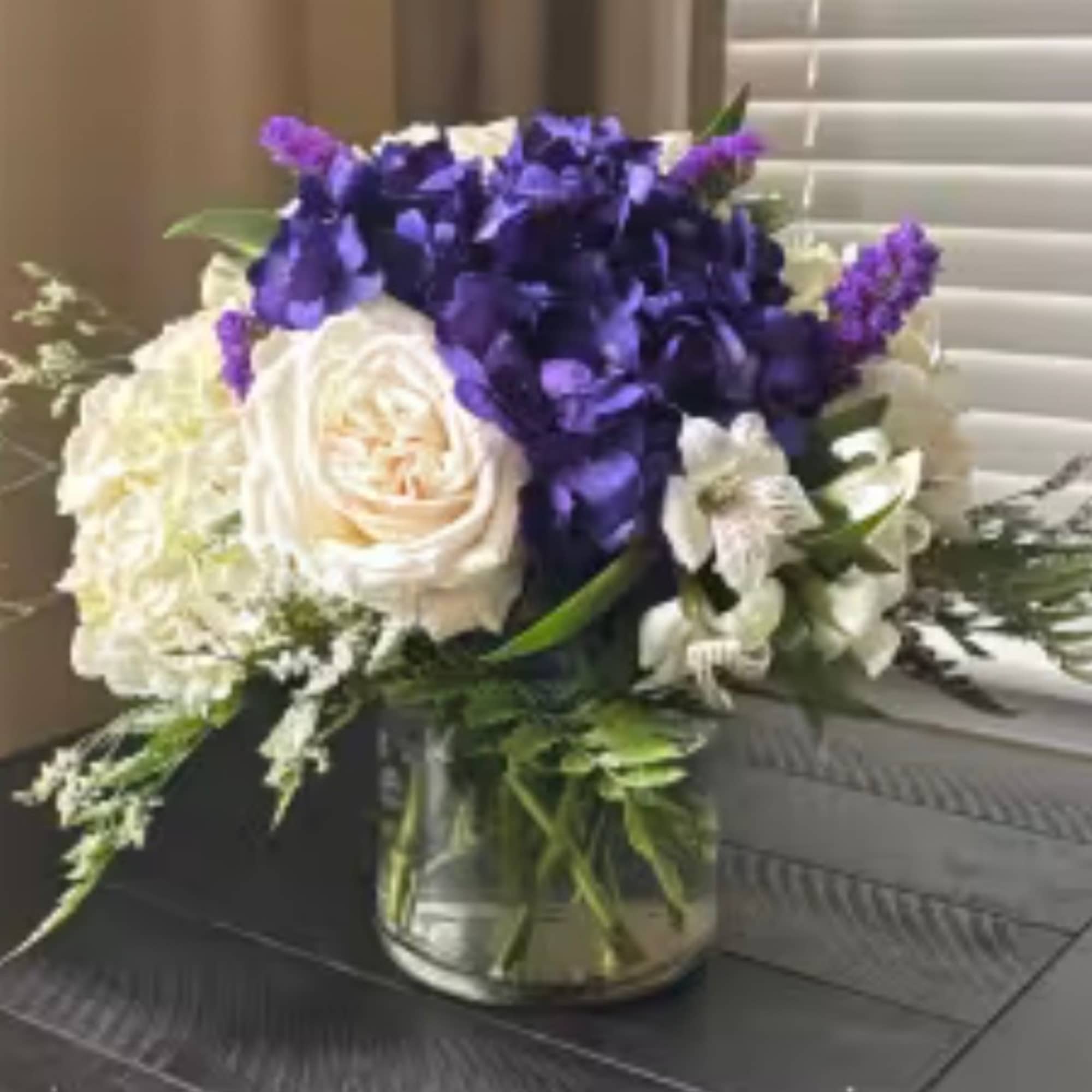 Purple and white flower arrangement in a glass vase