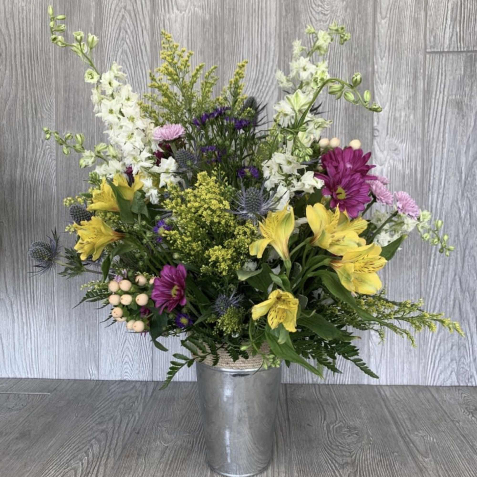Mixed bouquet in a metal bucket with yellow, white, and purple flowers