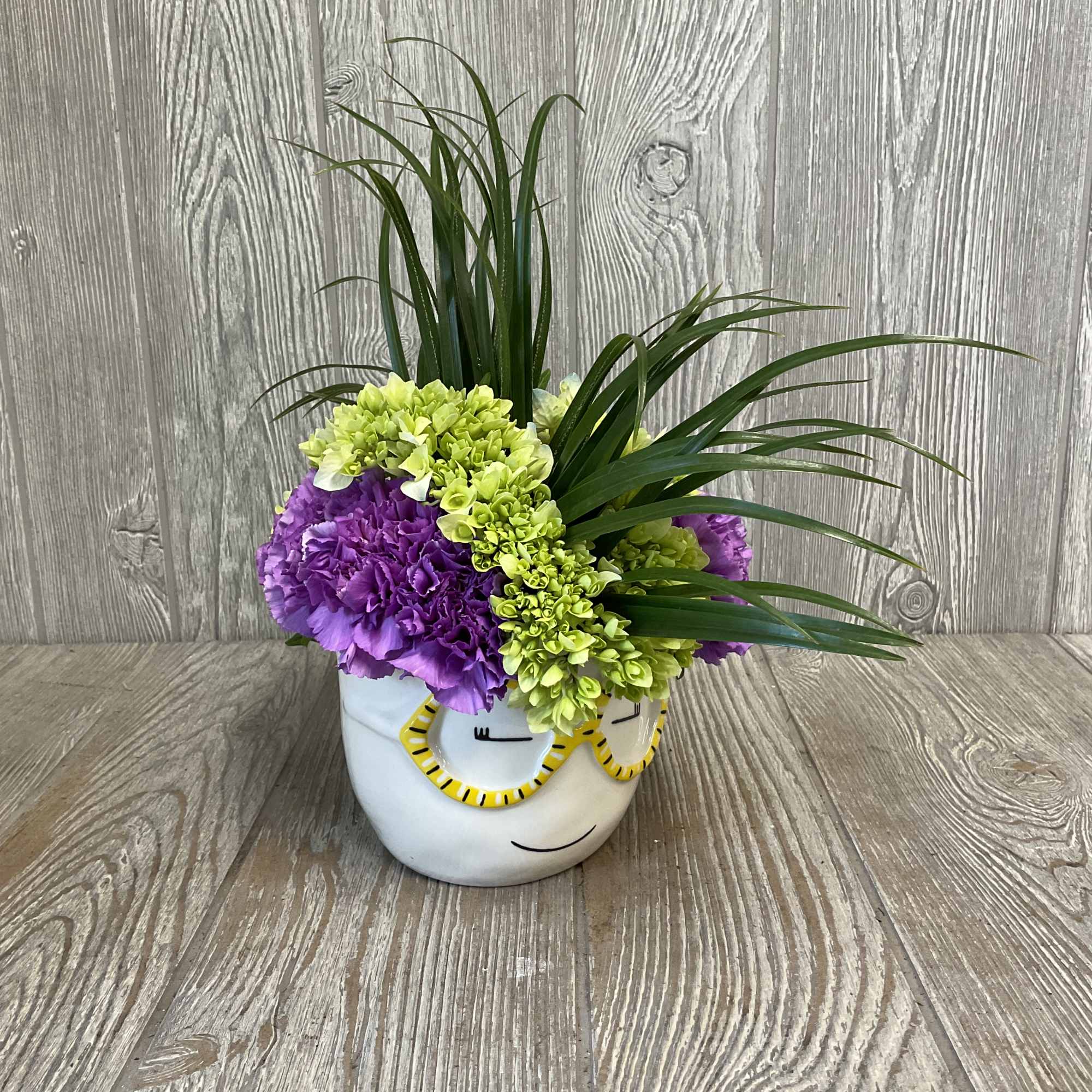 Purple and lime-green flowers in a white face planter