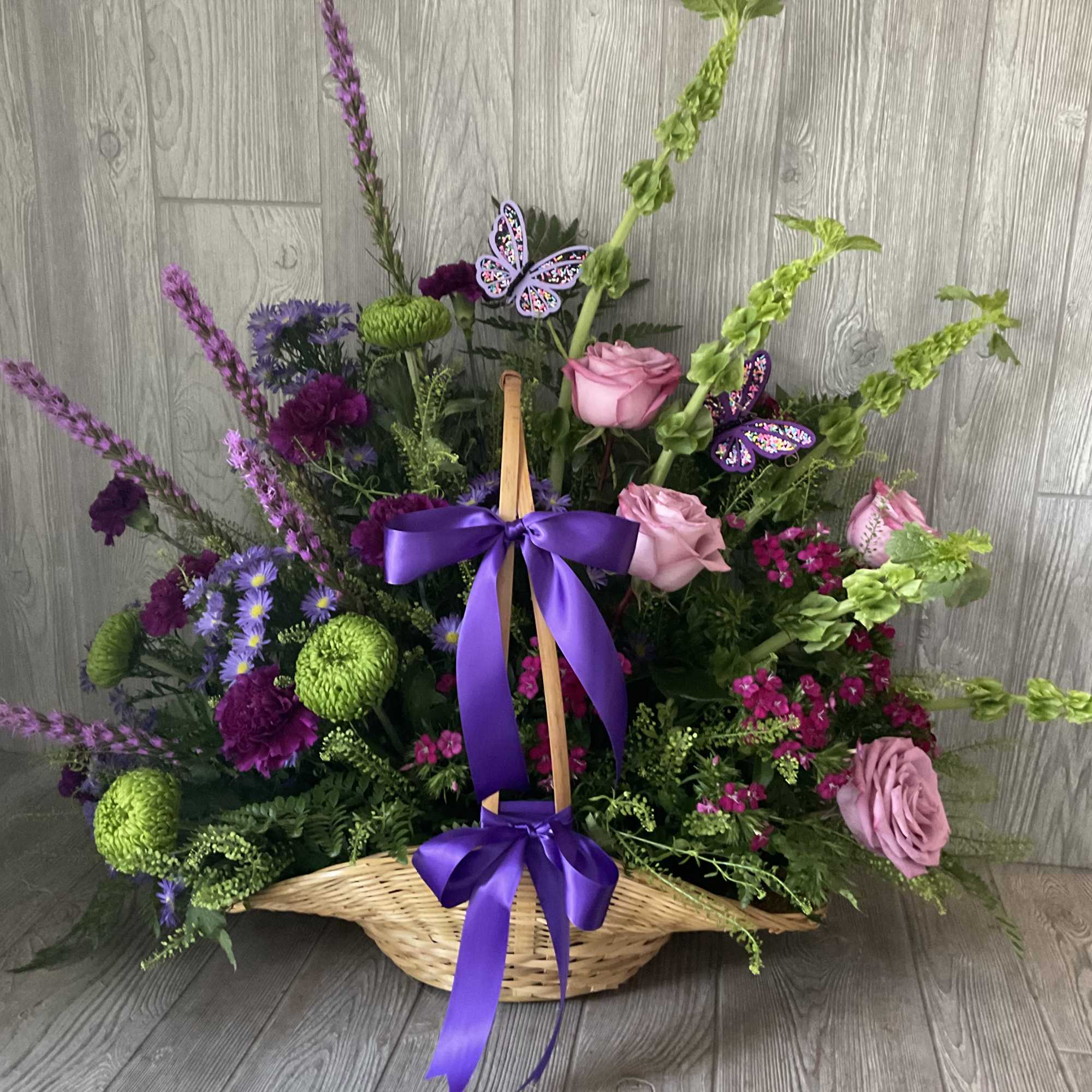 Basket arrangement of pink and purple flowers with a purple ribbon