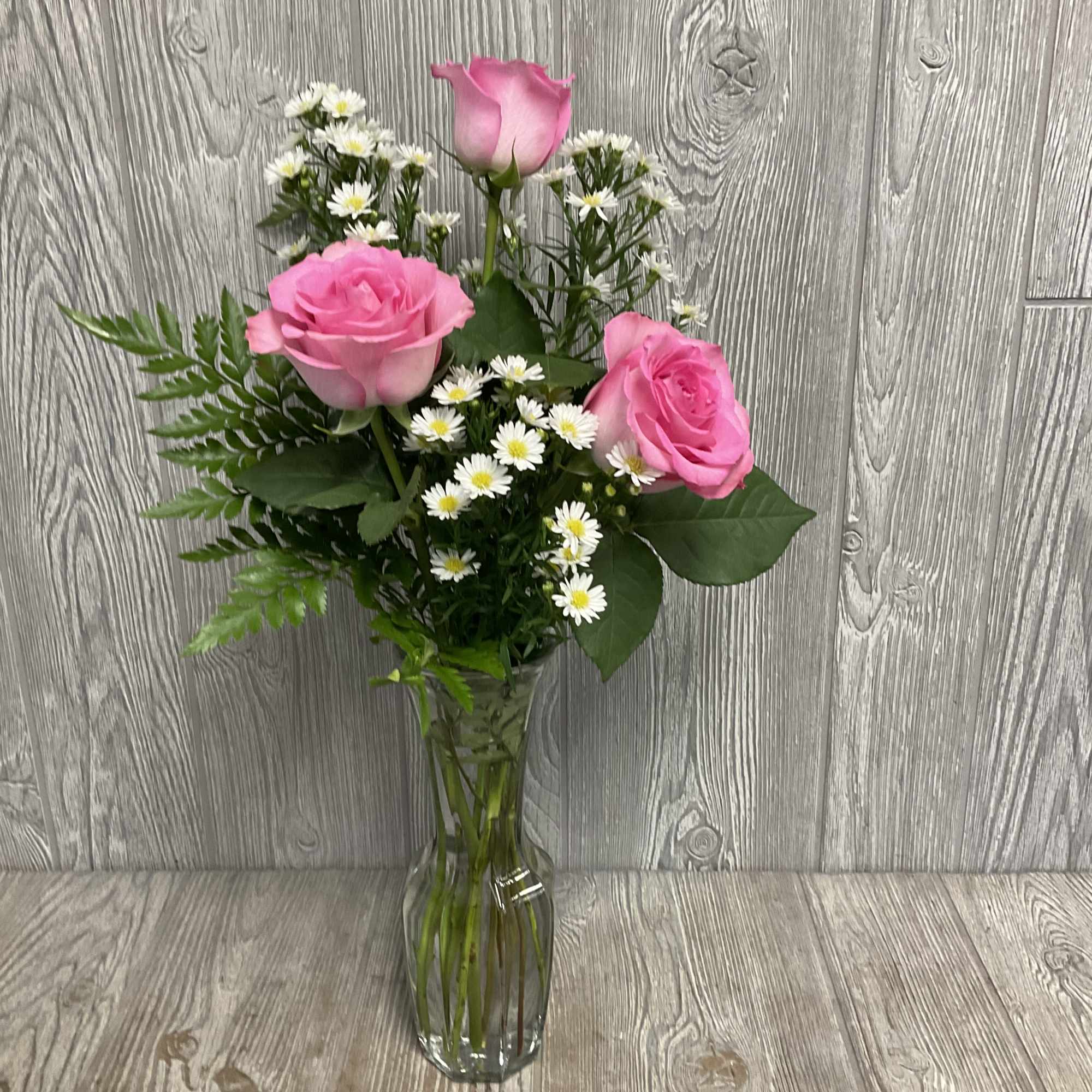 Pink roses and white daisies in a clear glass vase
