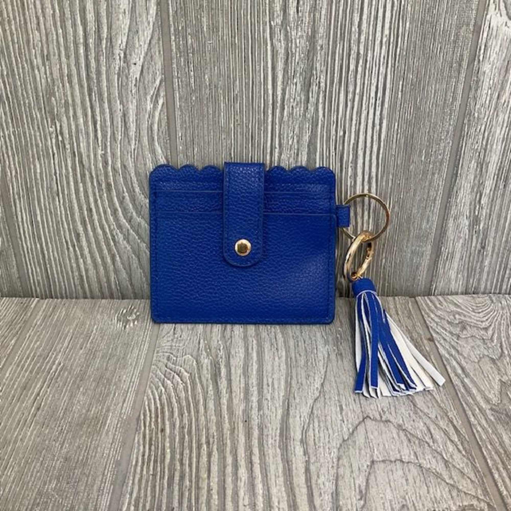 Blue card holder with a tassel keychain on a wood surface