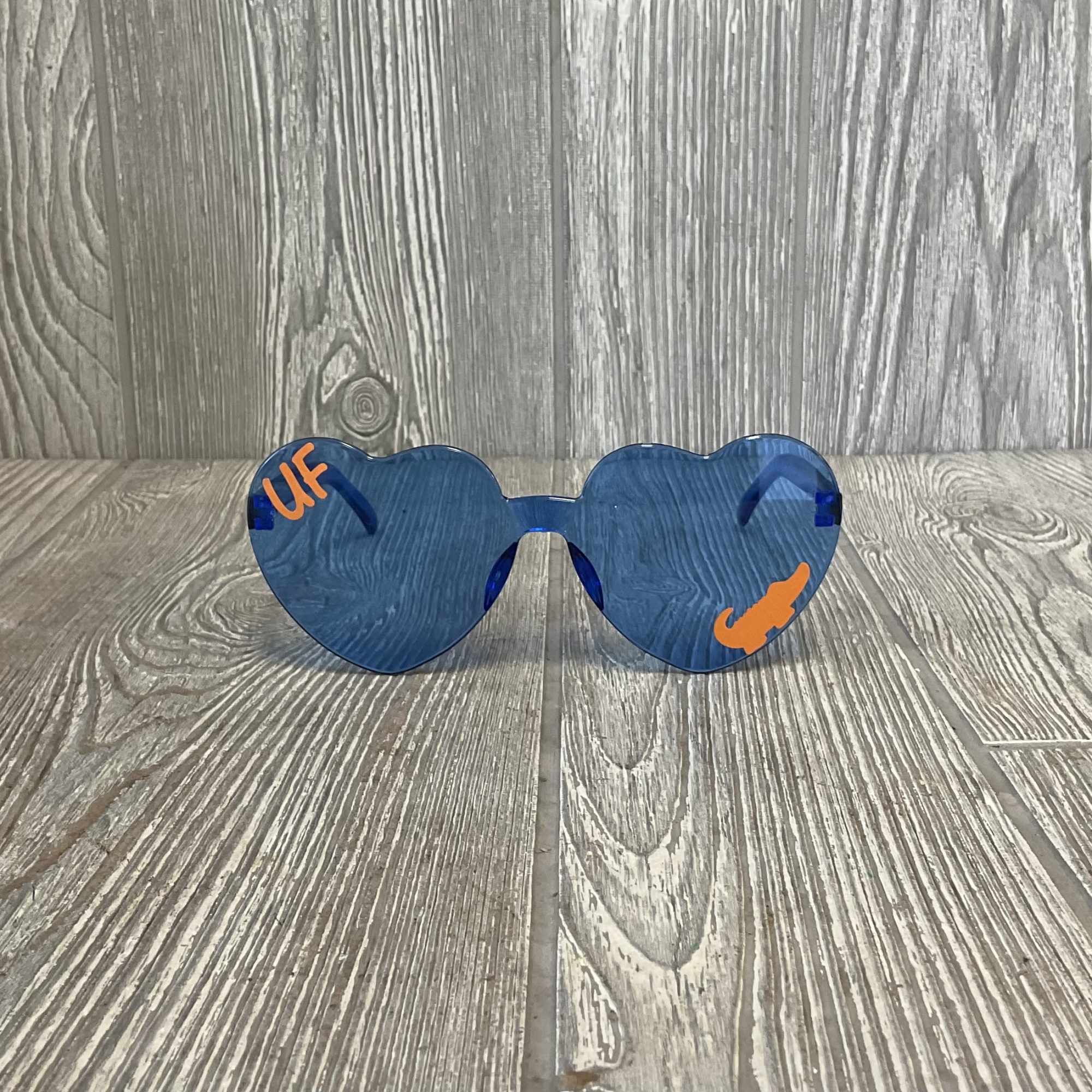 Blue heart-shaped sunglasses with orange accents on a wood floor