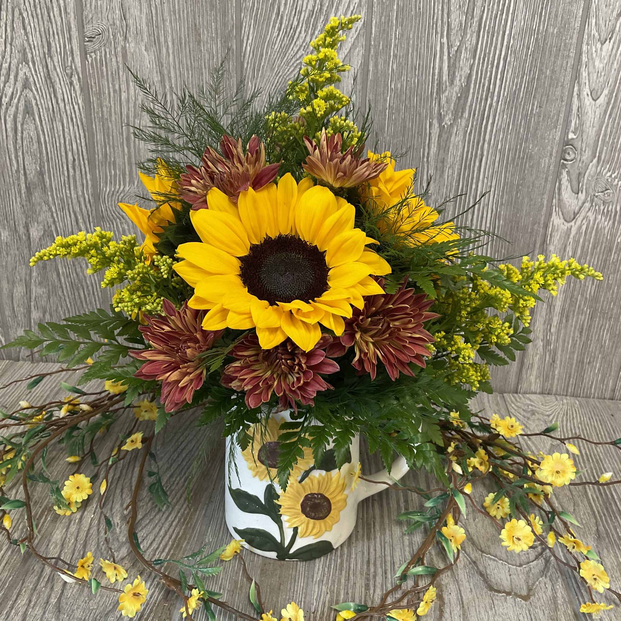 Sunflower arrangement in a painted mug with yellow and burgundy blooms