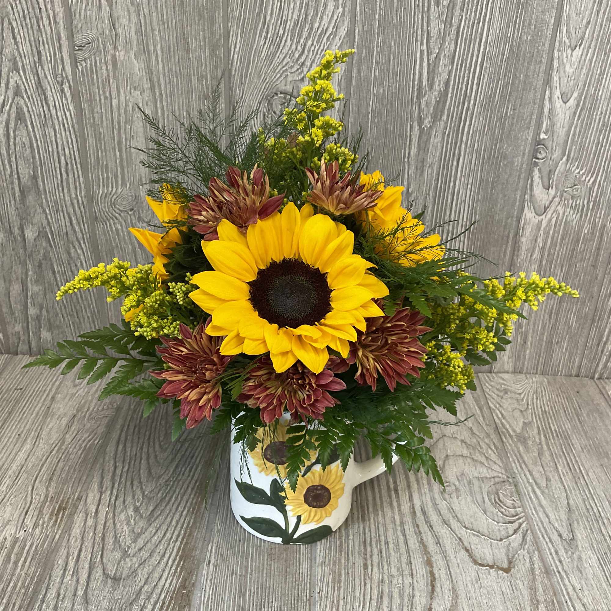 Sunflower and chrysanthemum arrangement in a painted mug vase