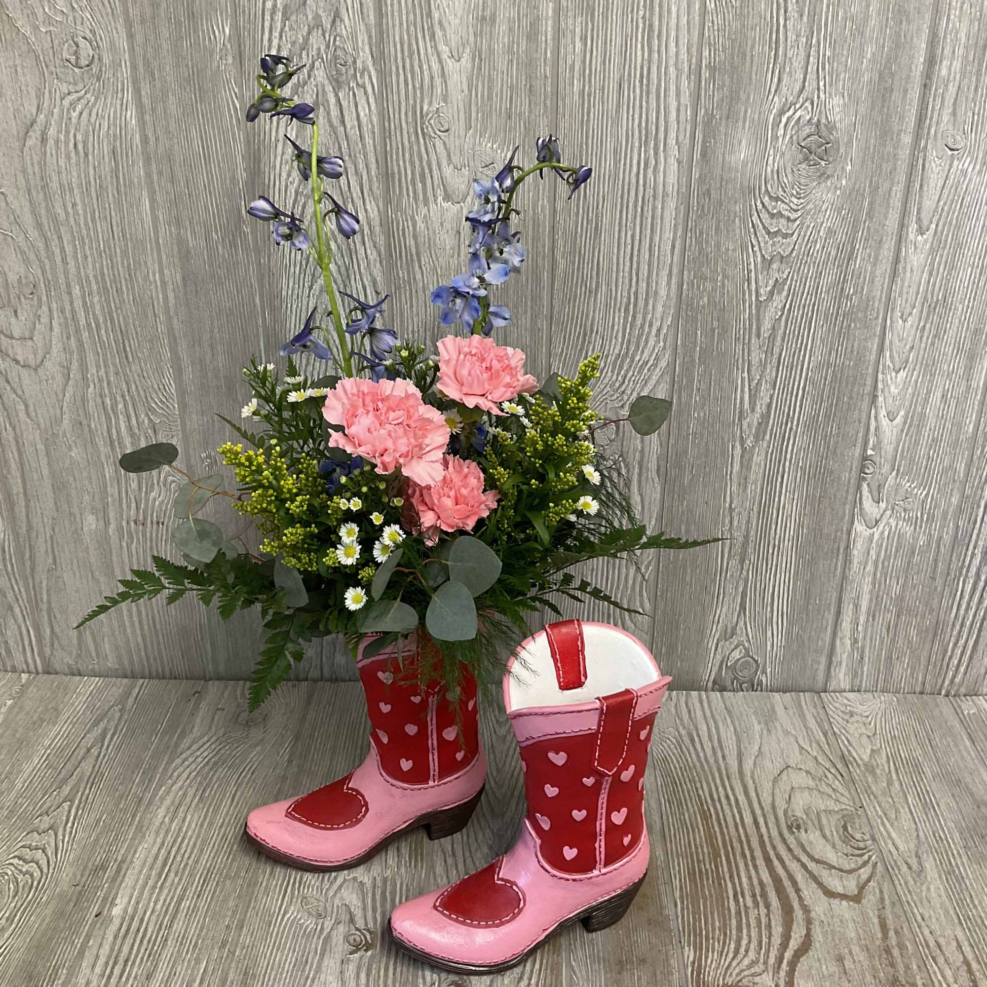 Pink and blue floral arrangement in pink cowboy boots