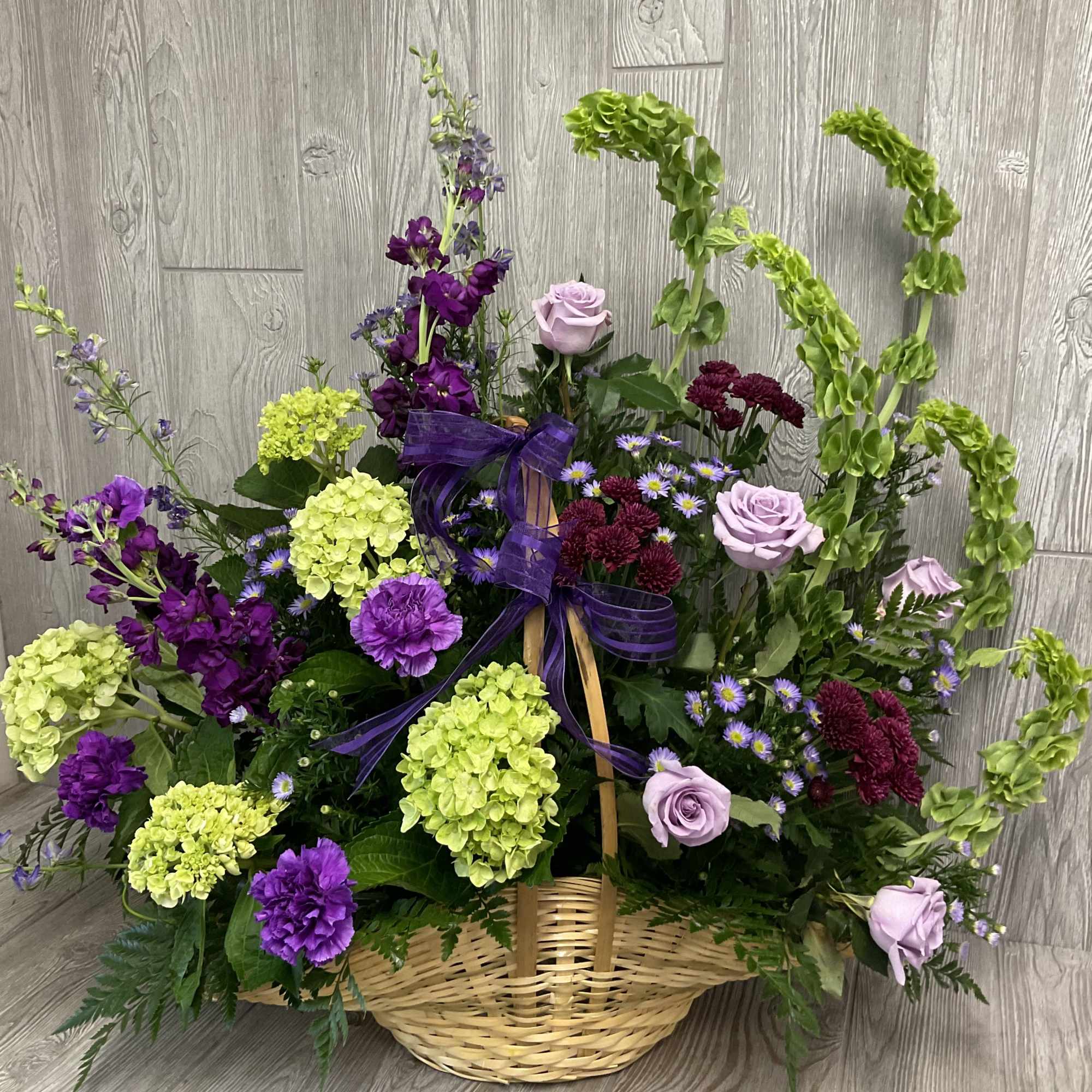 Basket arrangement of purple and green flowers with lavender roses