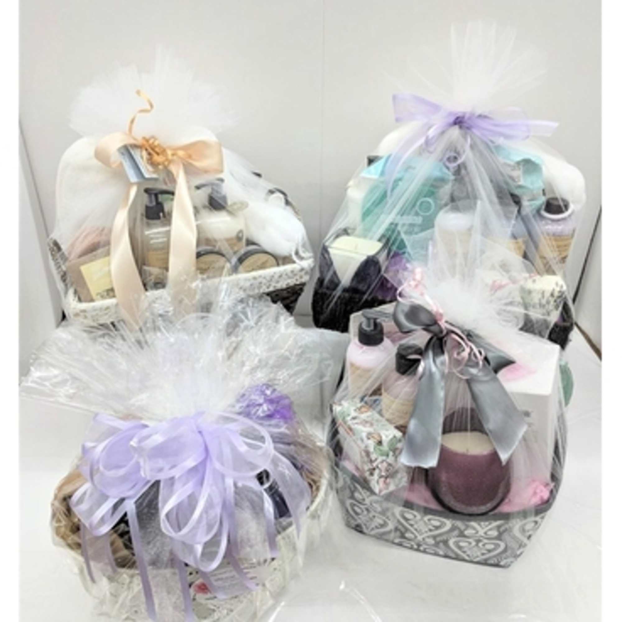 Four wrapped gift baskets with bath and body products and ribbons