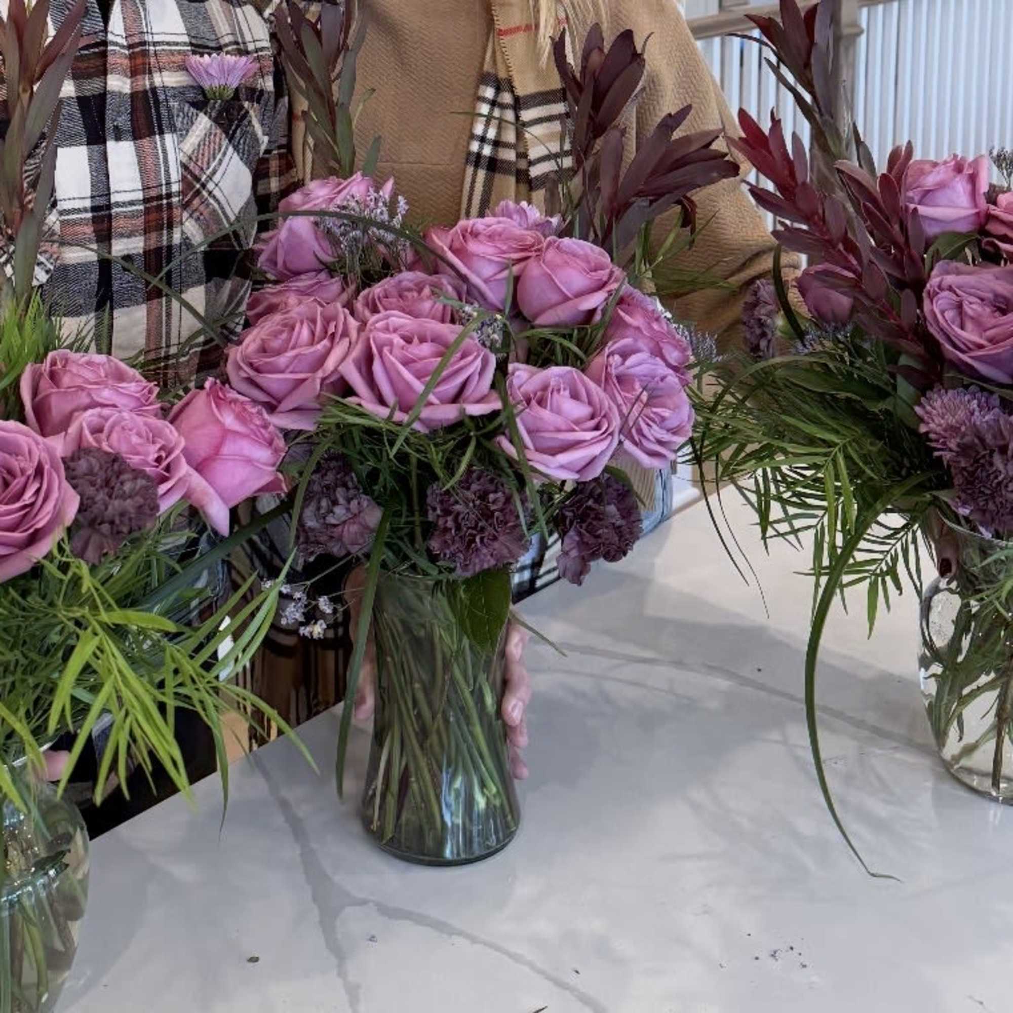 Pink rose bouquets in glass vases with dark foliage