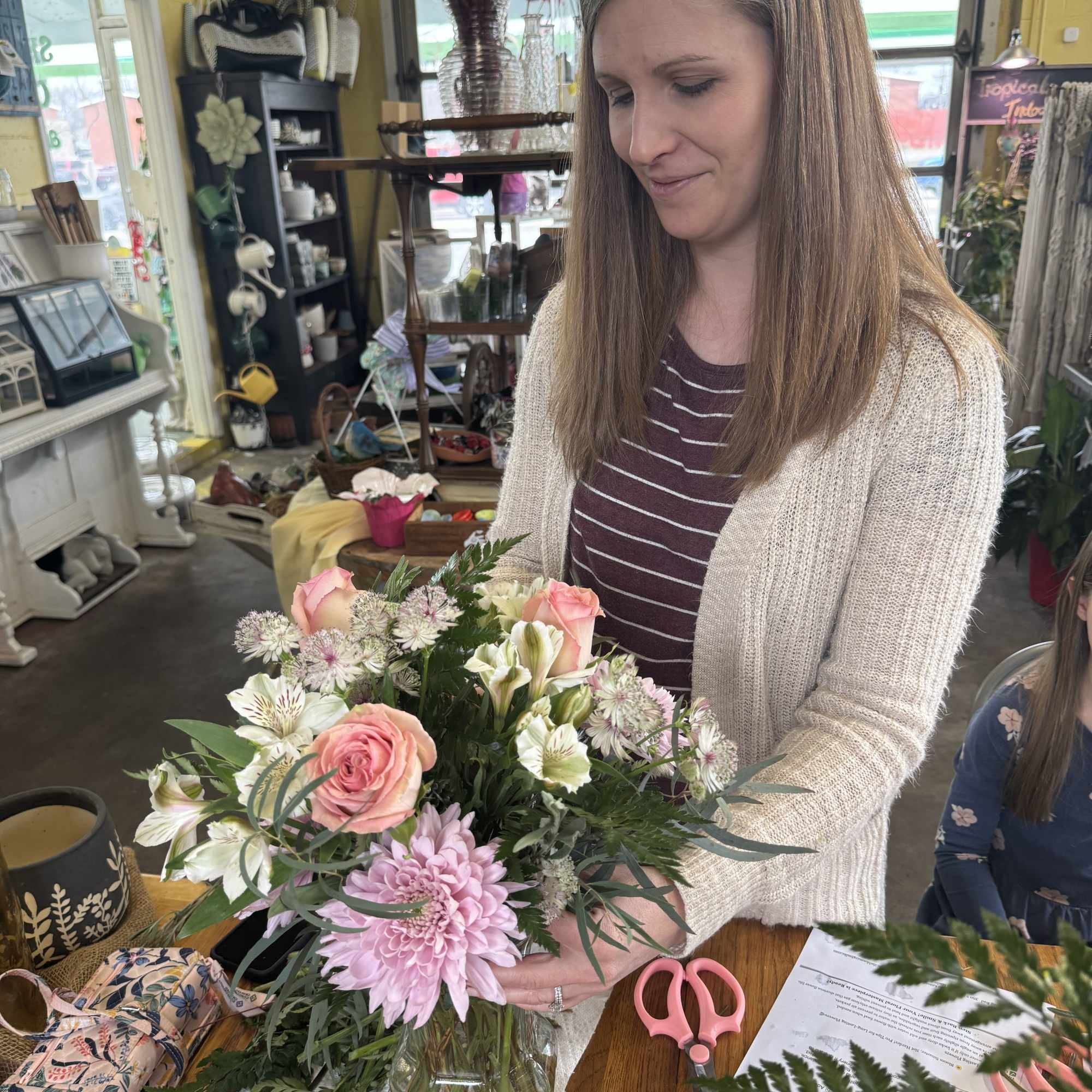 Woman holding a mixed bouquet of pink and white flowers in a glass vase