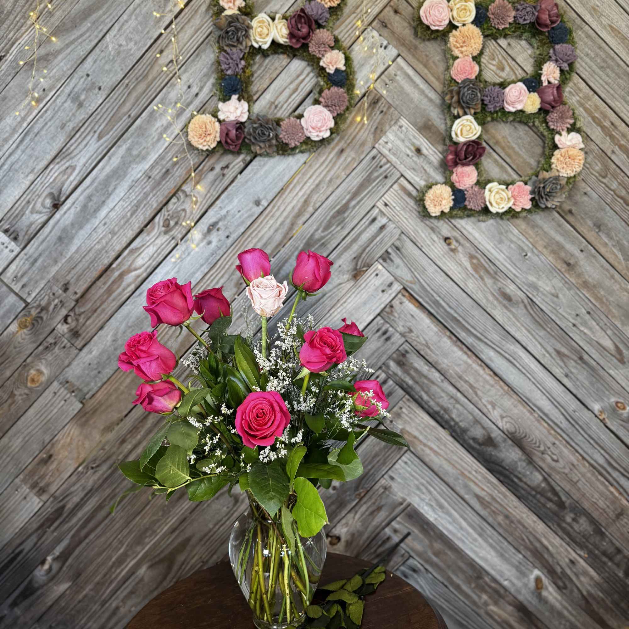 Pink rose bouquet in a clear glass vase with a rose on the table