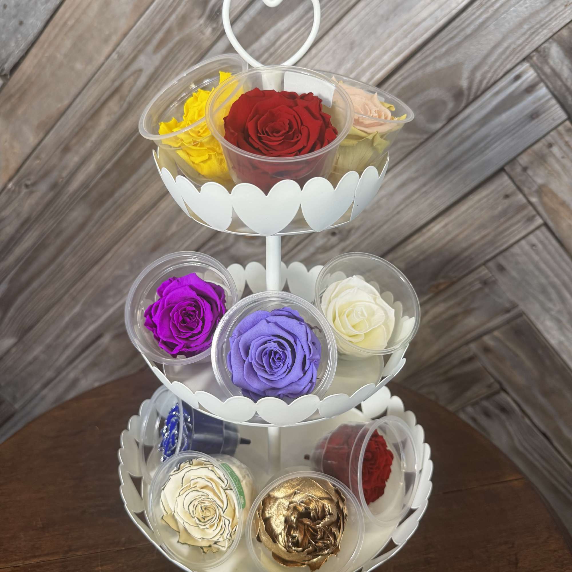 Tiered stand holding colorful roses in clear cups