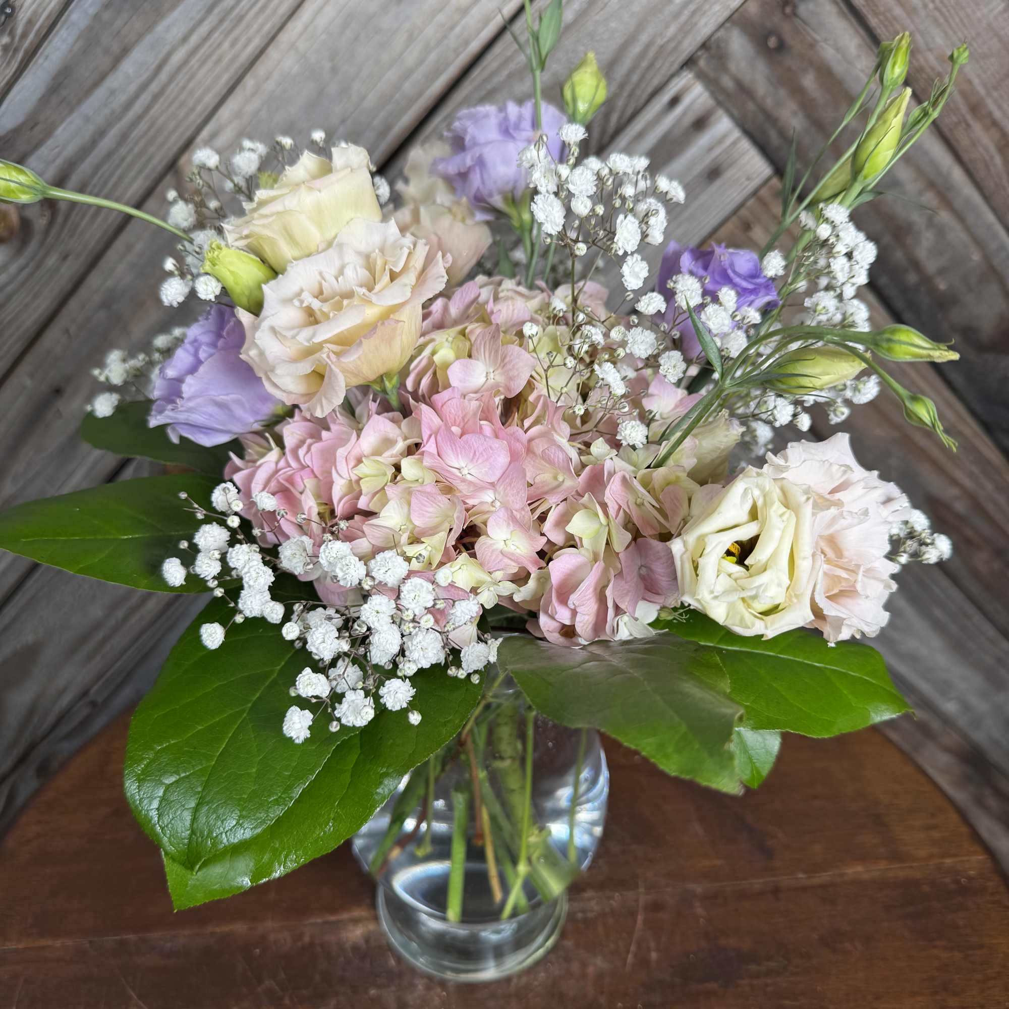 Pastel bouquet of hydrangeas, lisianthus, and baby's breath in a glass vase