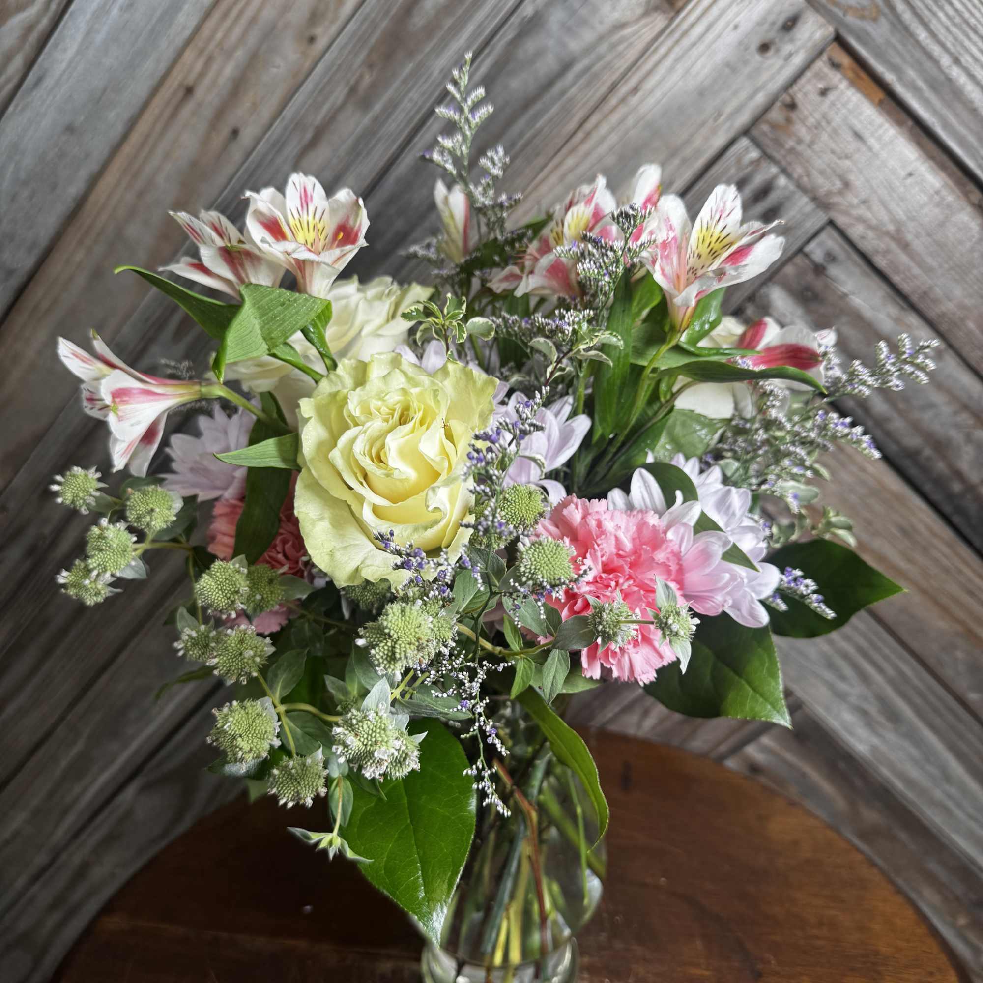 Mixed bouquet in a clear glass vase with pale yellow roses and pink-white blooms