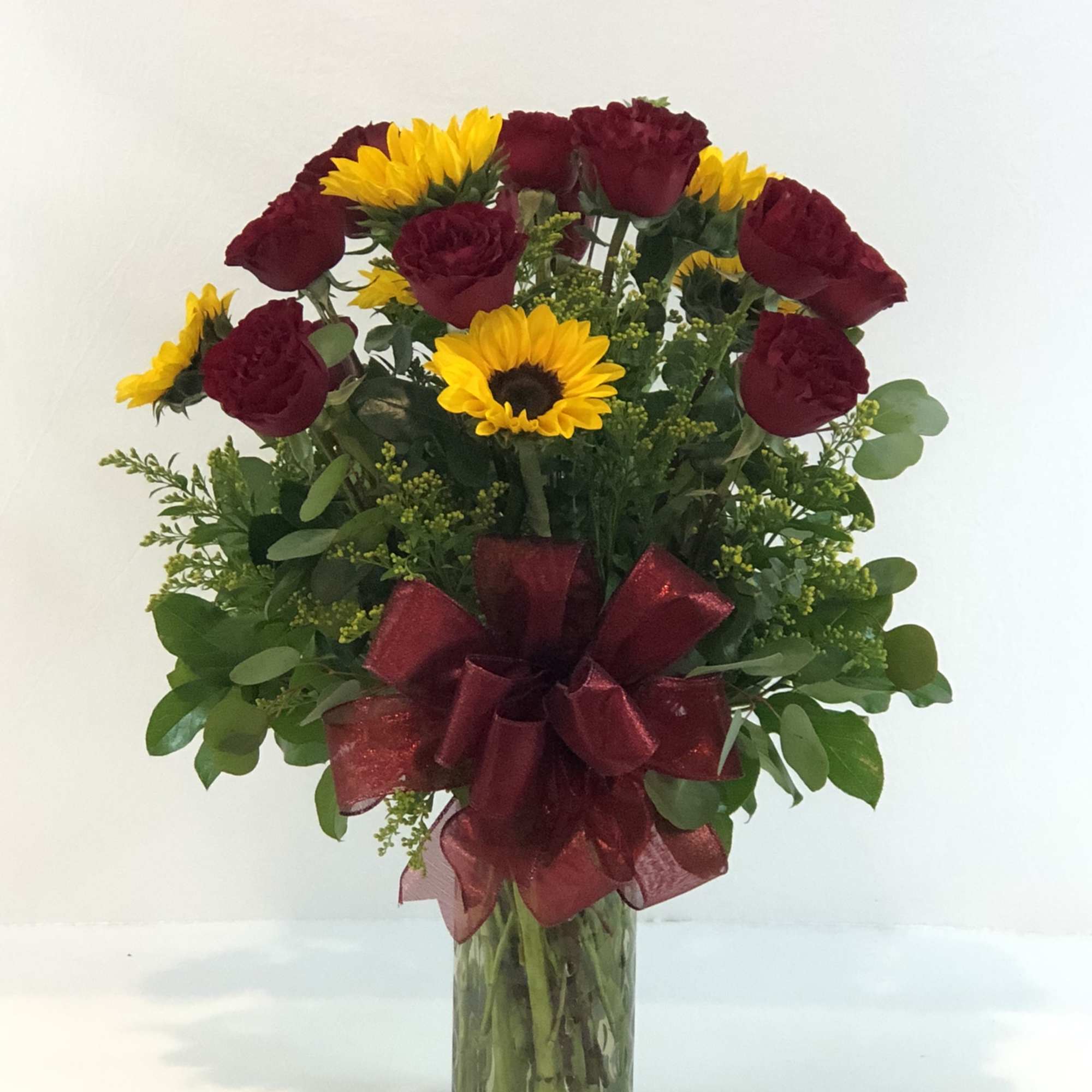 Bouquet of red roses and yellow sunflowers in a glass vase