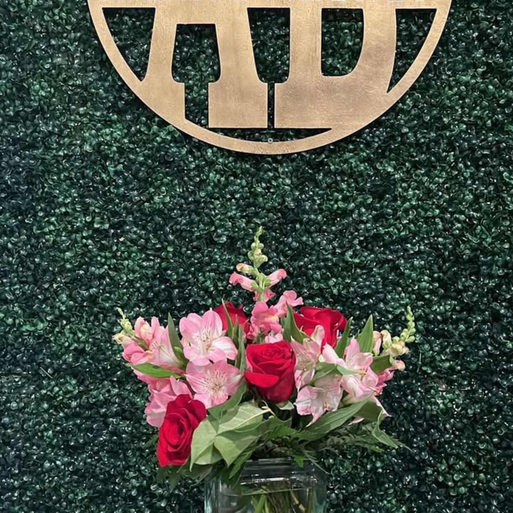 Pink and red flower arrangement in a glass vase on a pedestal