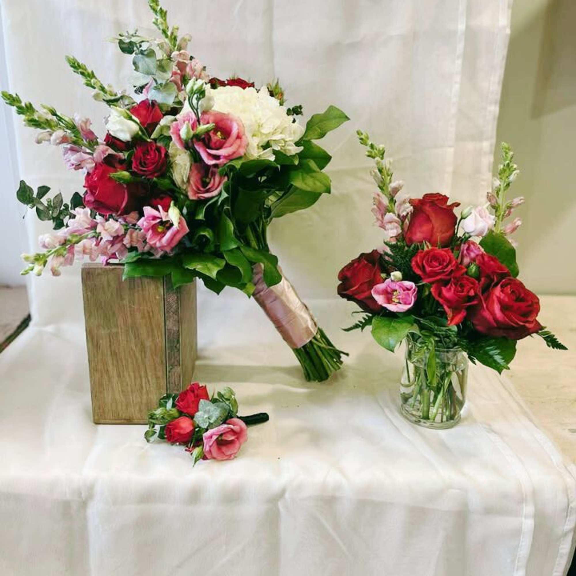Bouquet of red and pink roses with white blooms, plus a matching boutonniere