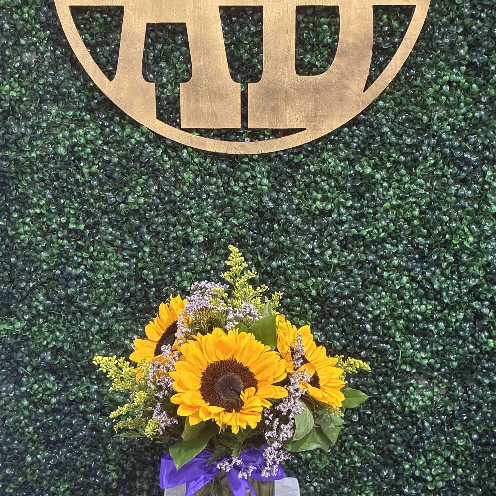 Sunflower bouquet in a glass vase with a purple ribbon