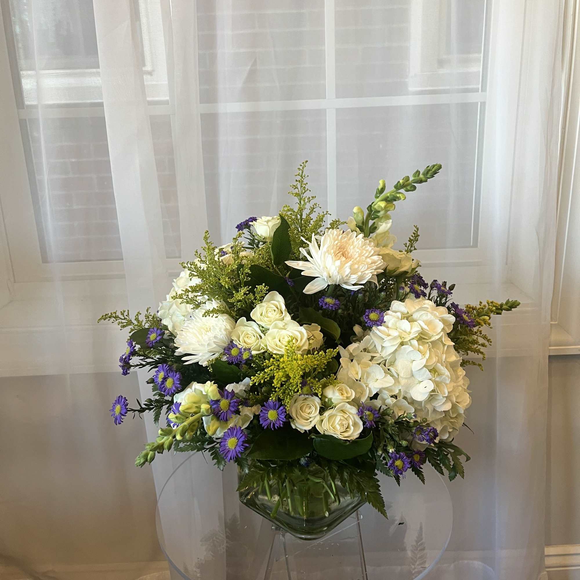 White and purple floral arrangement in a clear glass vase