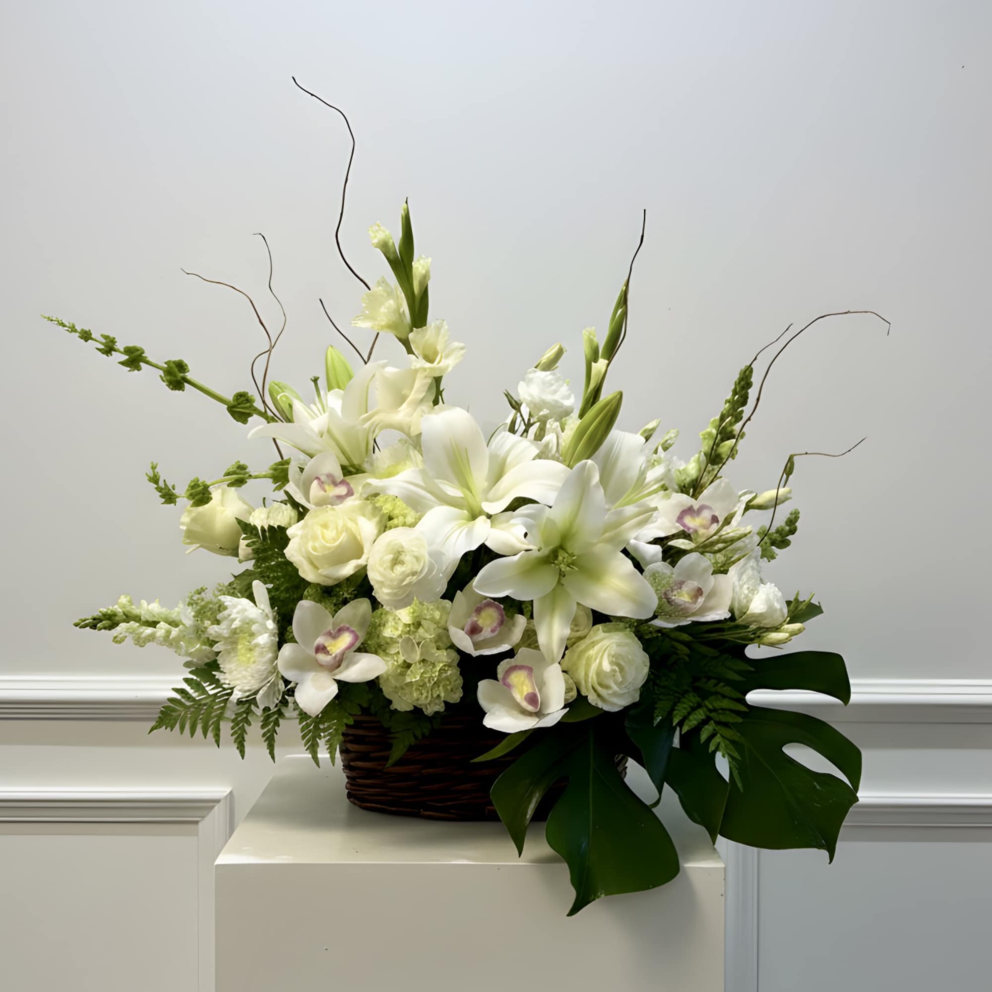 White lilies and orchids arranged in a wicker basket