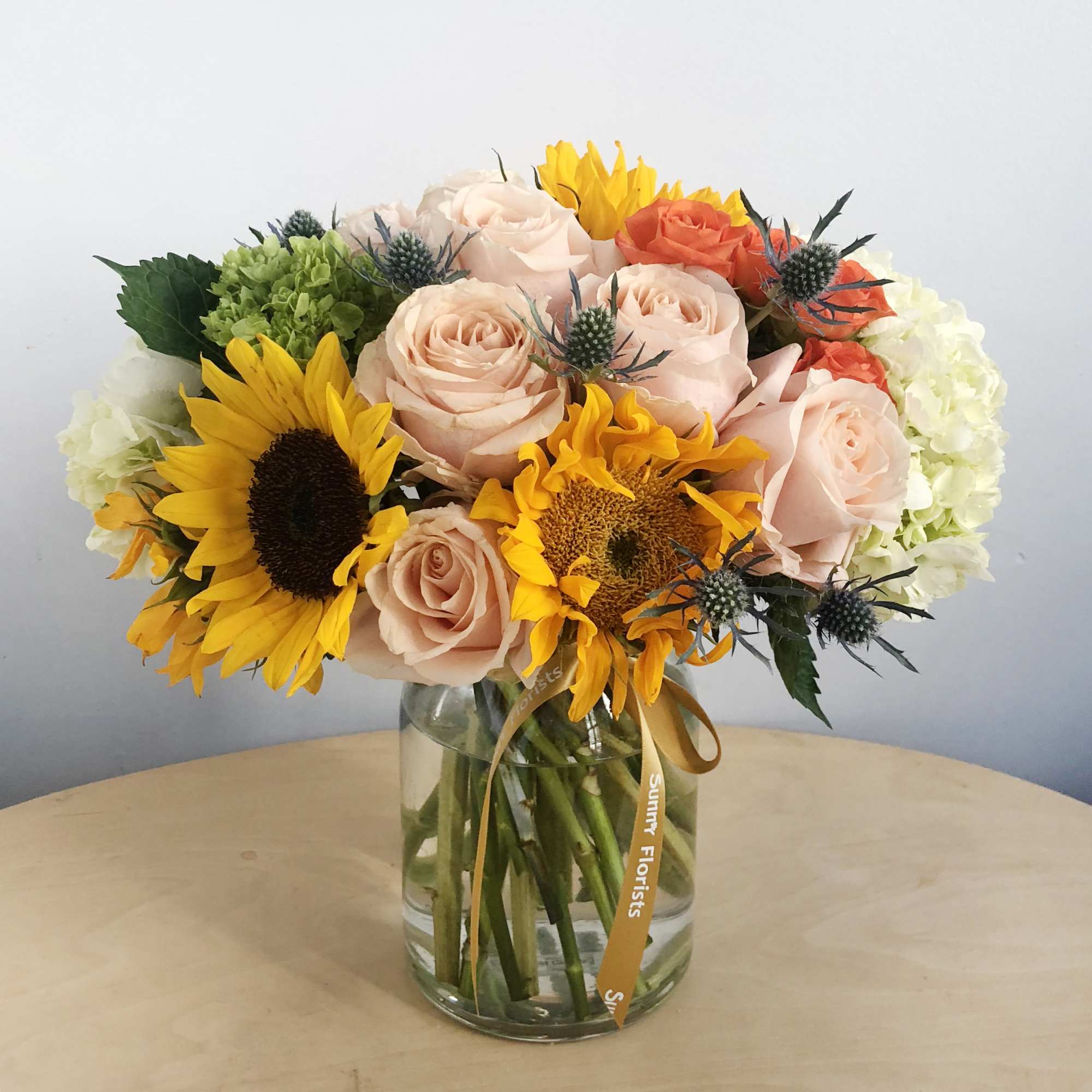Bouquet of sunflowers and pale pink roses in a glass vase