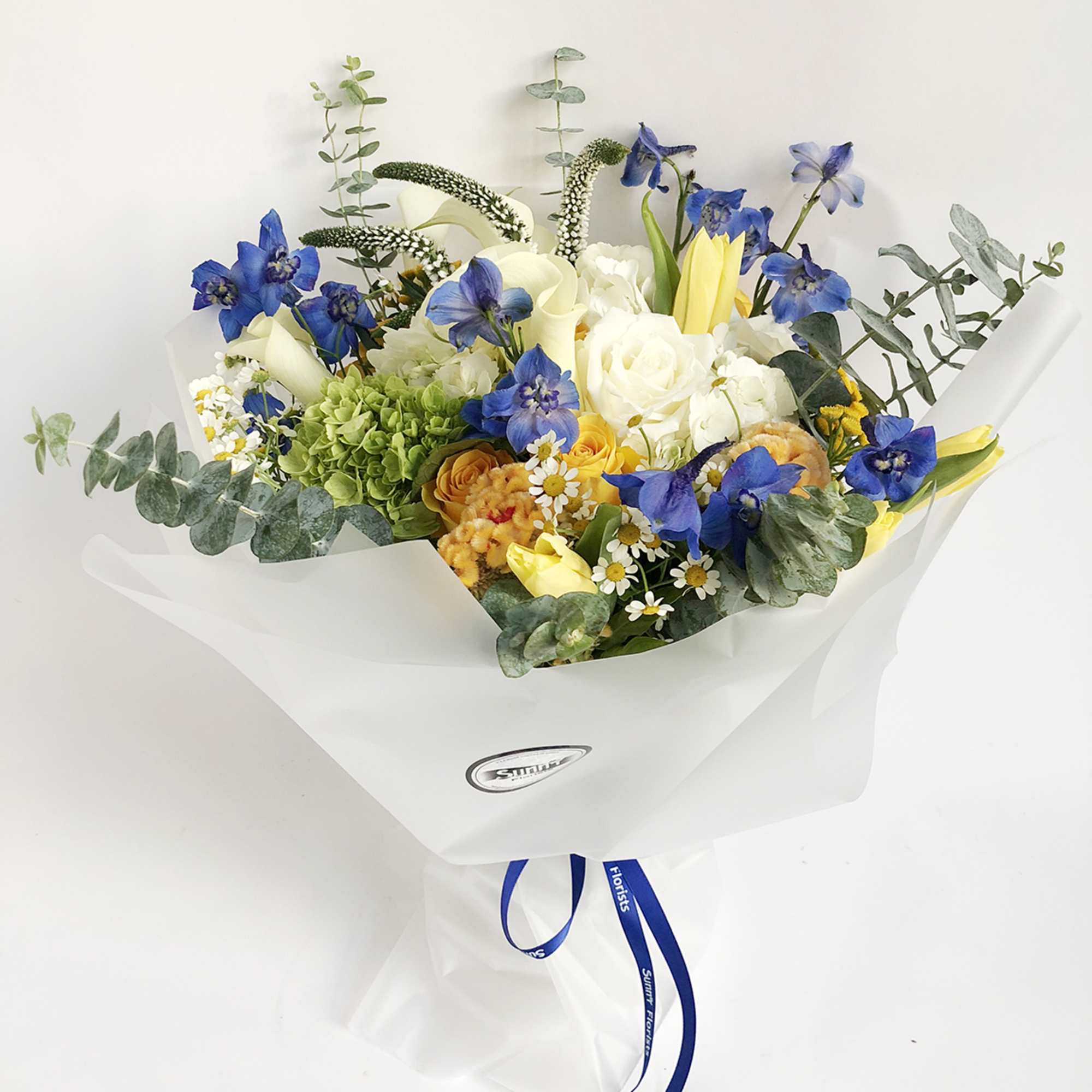Bouquet of blue, white, and yellow flowers wrapped in white paper