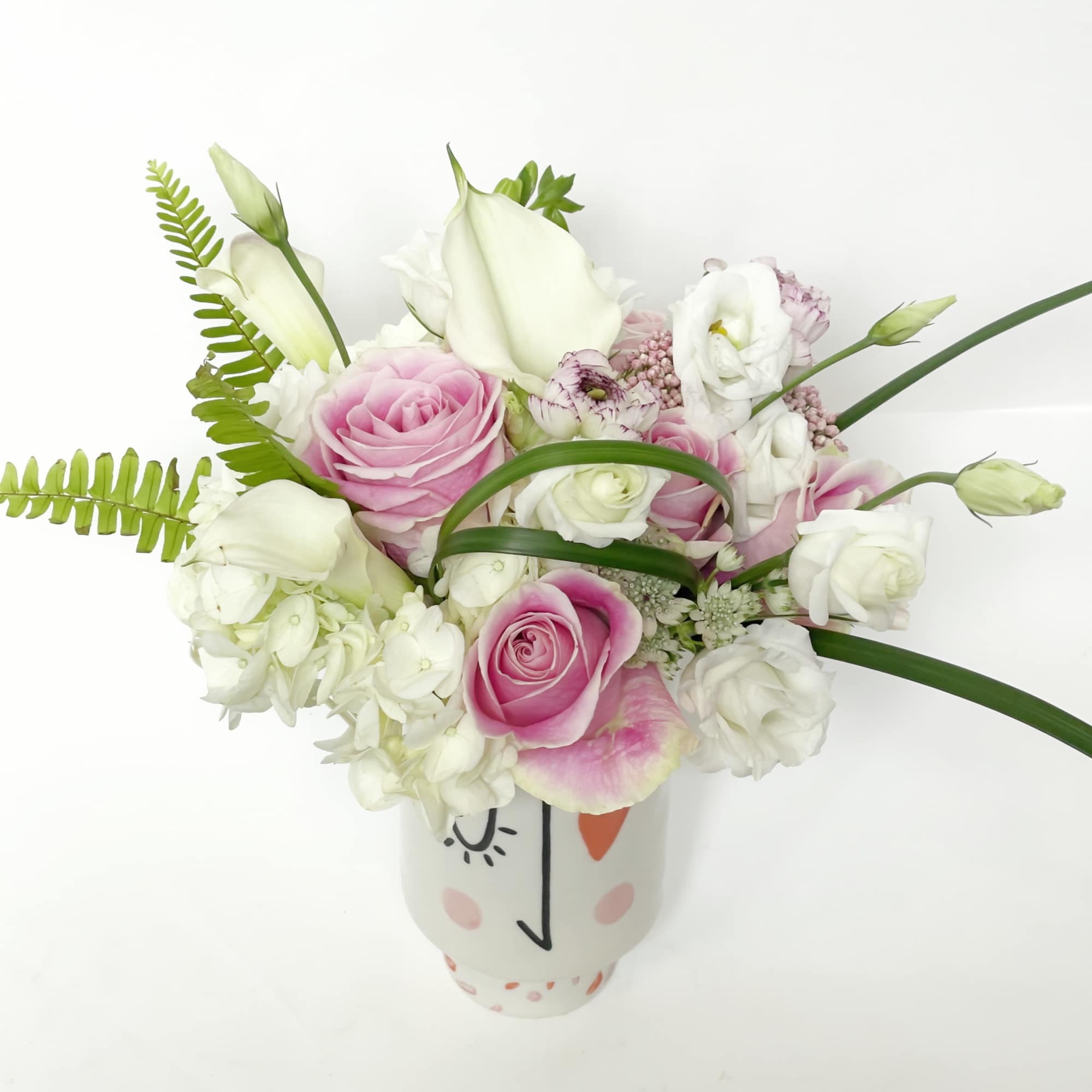 Pink and white roses arranged in a decorative ceramic vase