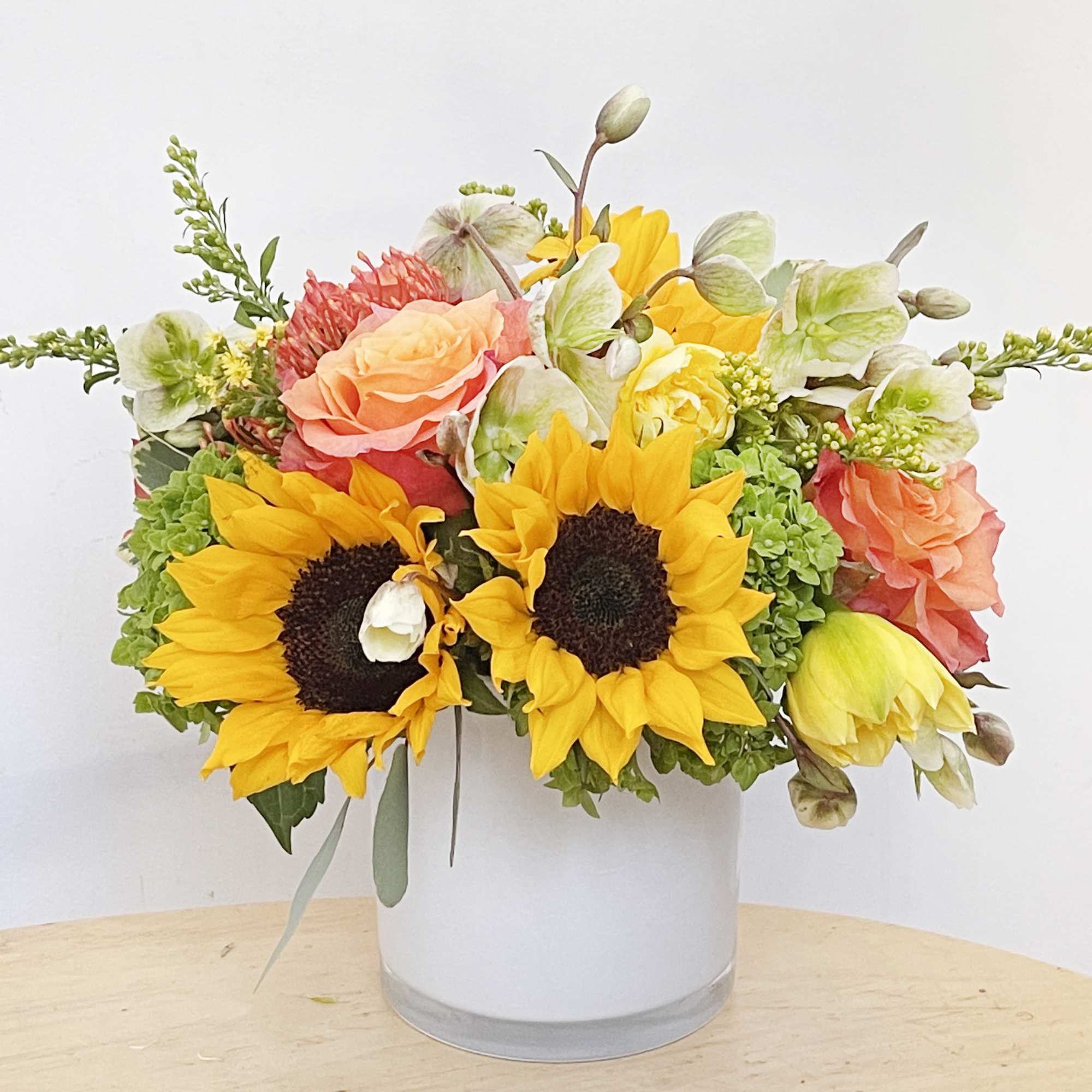 This arrangement include orange free spirit roses, sunflowers, hellebore, hydrangea, daffodils and, photo 2 of 2
