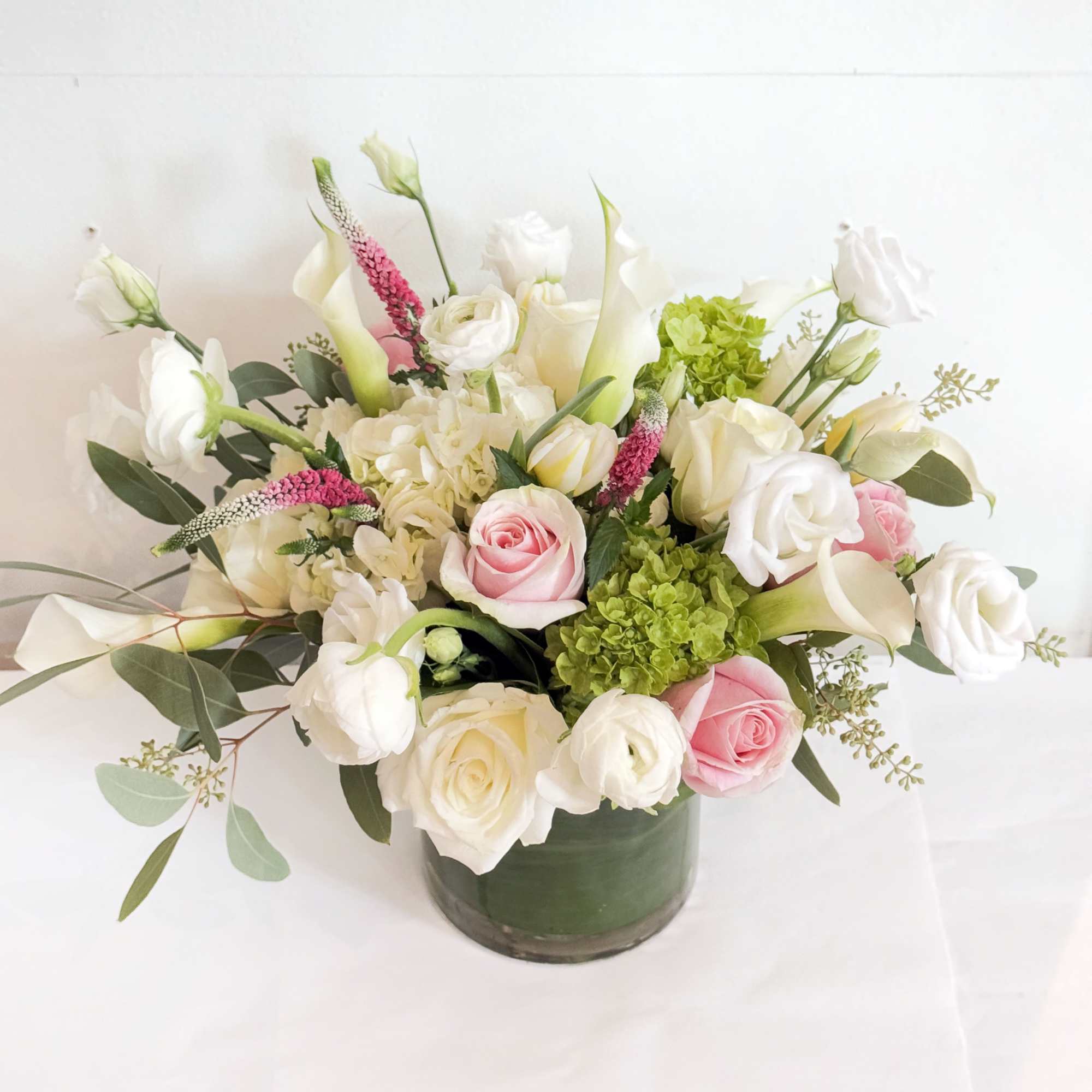 Pink and white roses arranged in a green glass vase