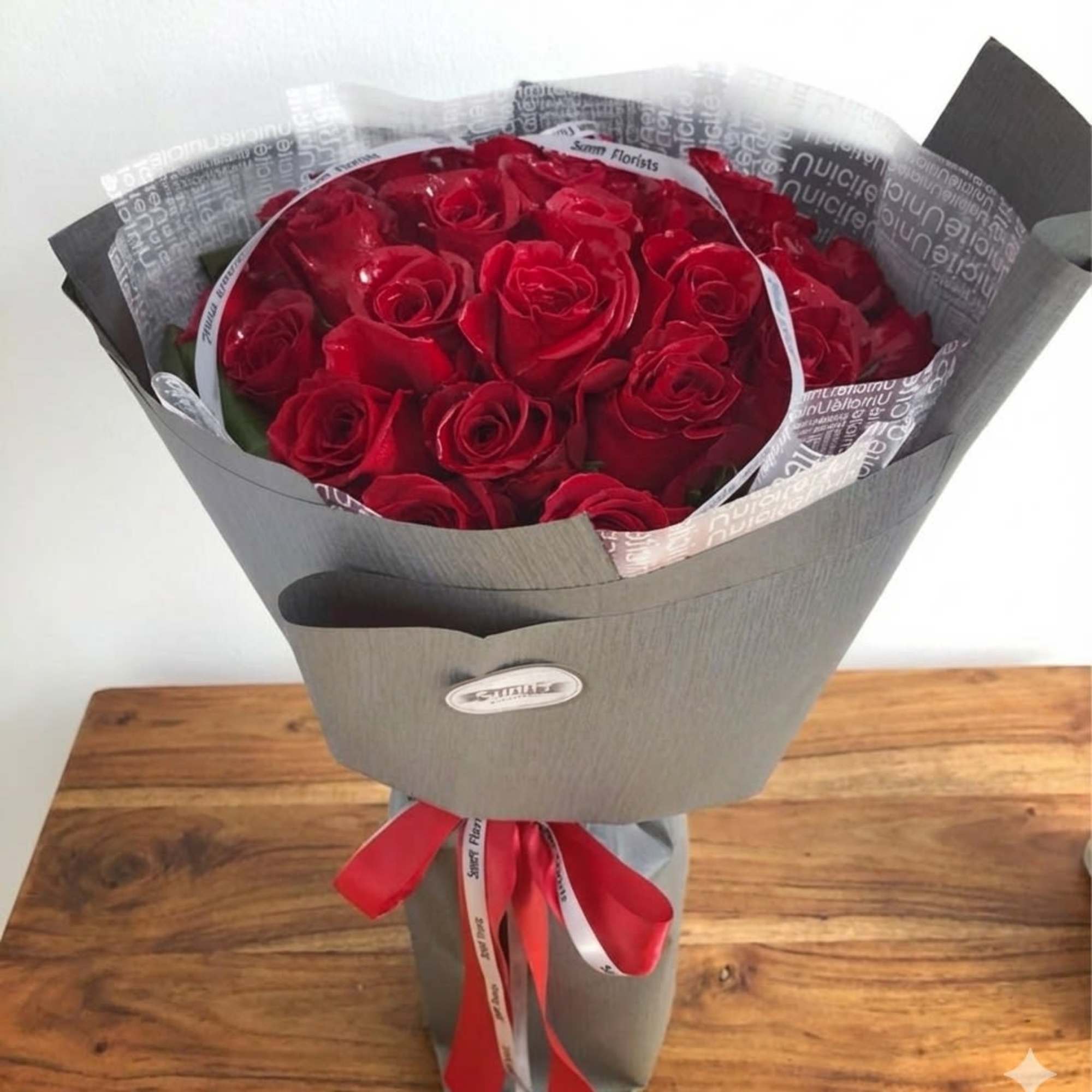 Bouquet of red roses wrapped in gray paper with a red ribbon