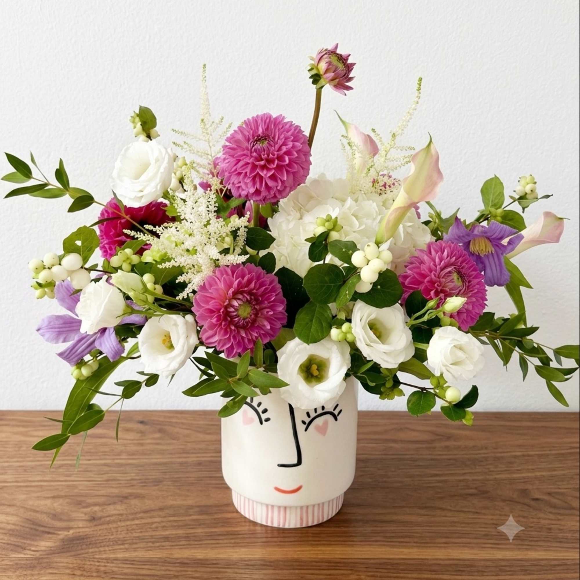 Mixed bouquet in a face-painted ceramic vase with pink, white, and purple blooms