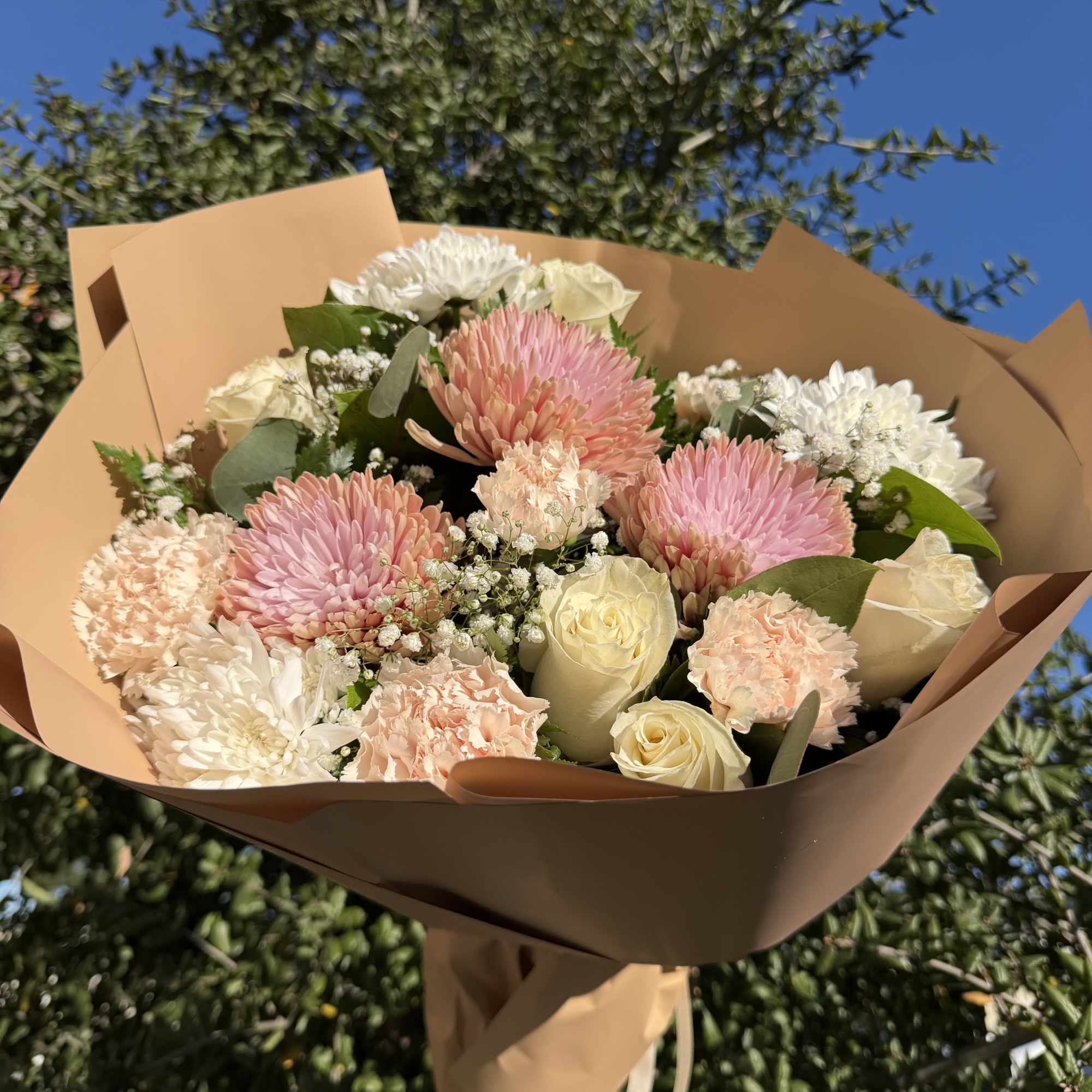 Bouquet of pink and white flowers wrapped in tan paper