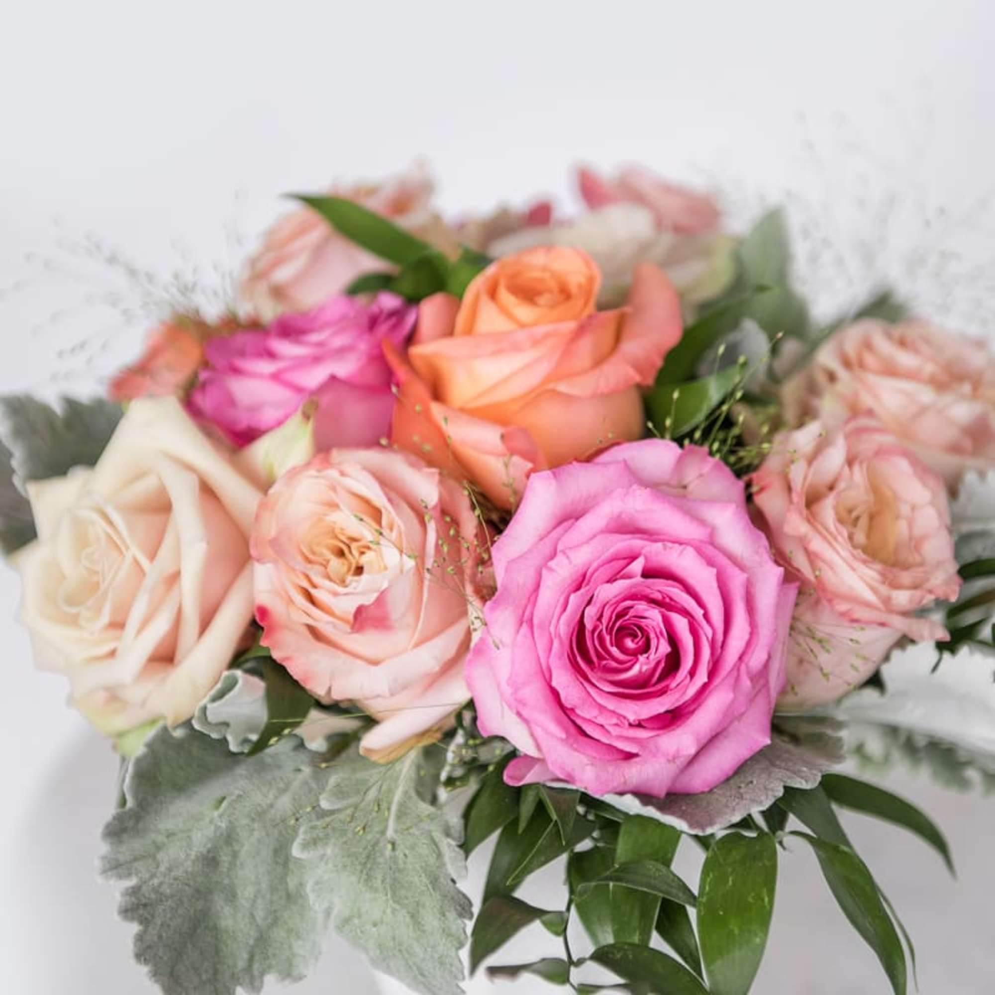 Bouquet of pink, peach, and white roses with greenery