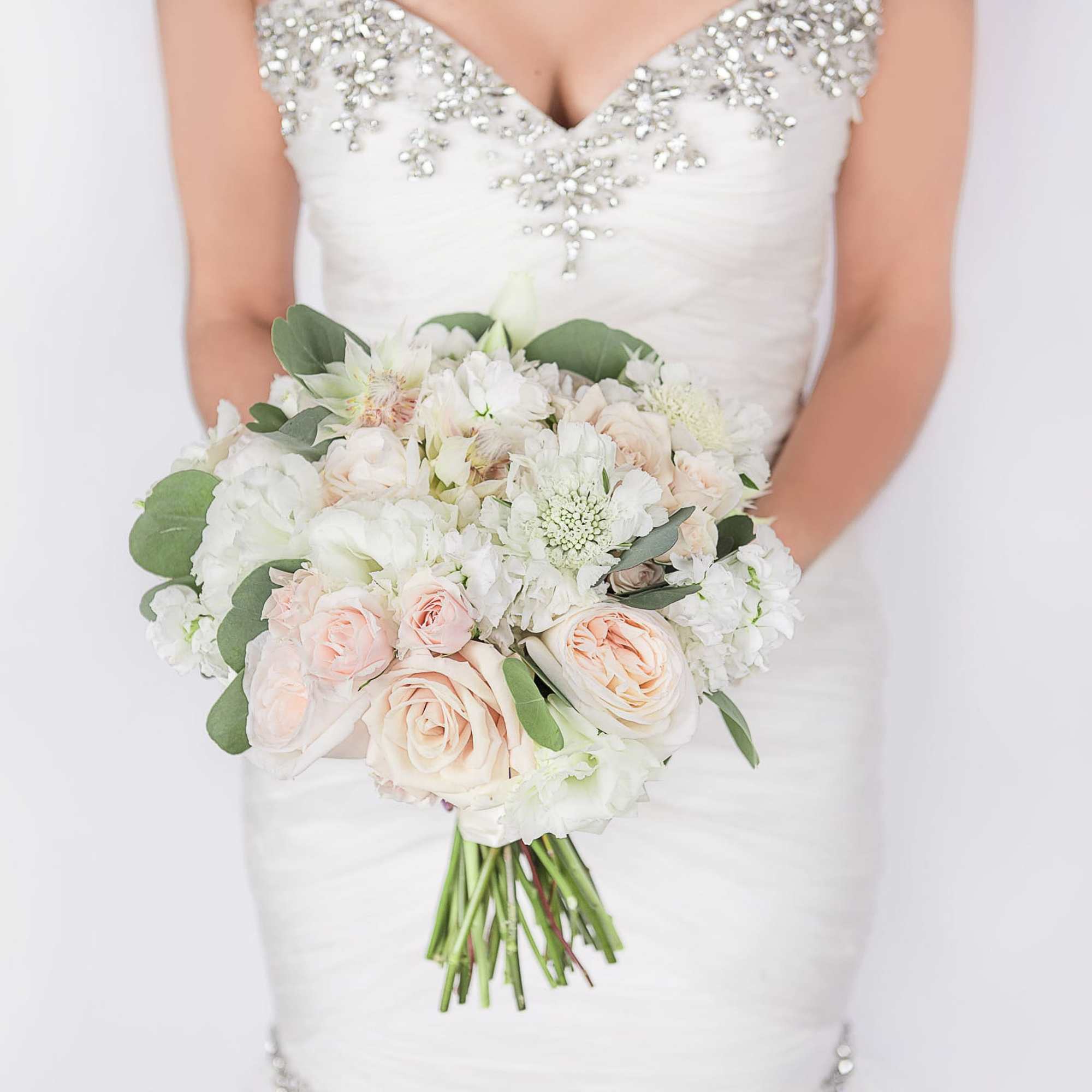 Bride holding a white and blush bouquet with roses and greenery