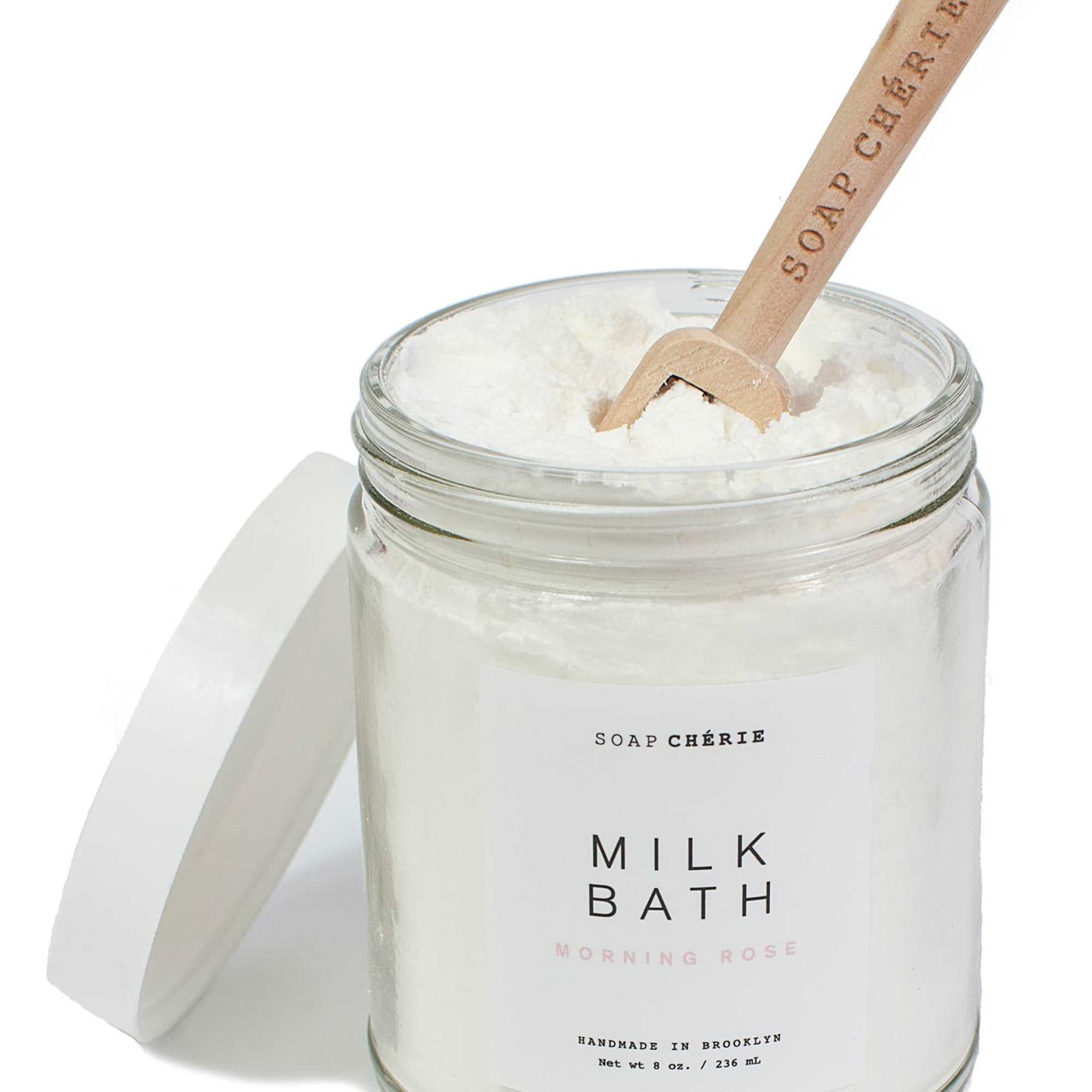 Jar of milk bath powder with a wooden scoop