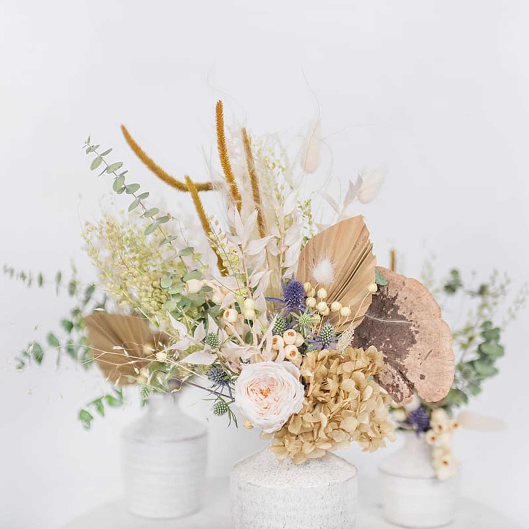 Dried floral arrangement with beige and white blooms in a white vase