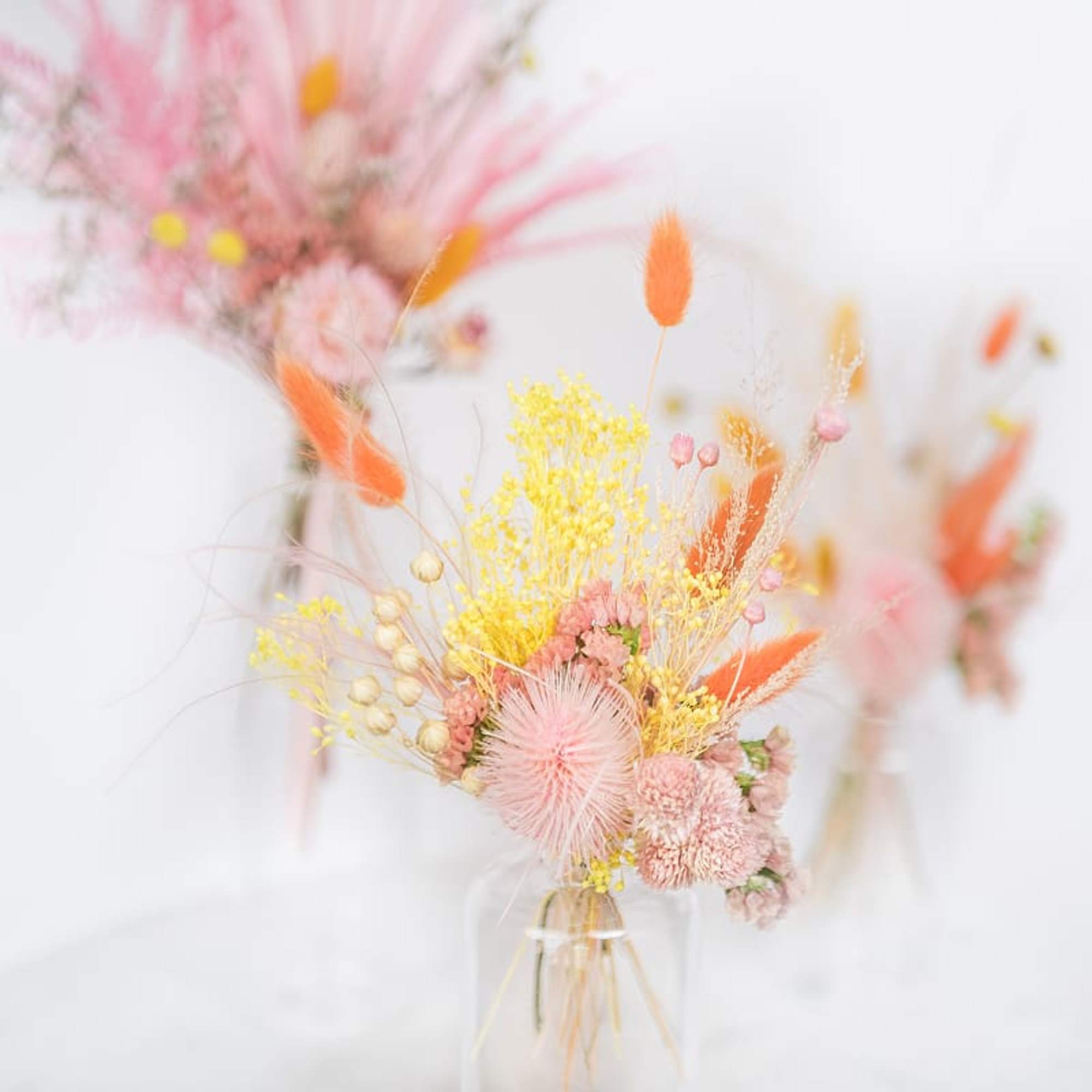 Pastel dried flower arrangement in a clear vase with pink and orange accents