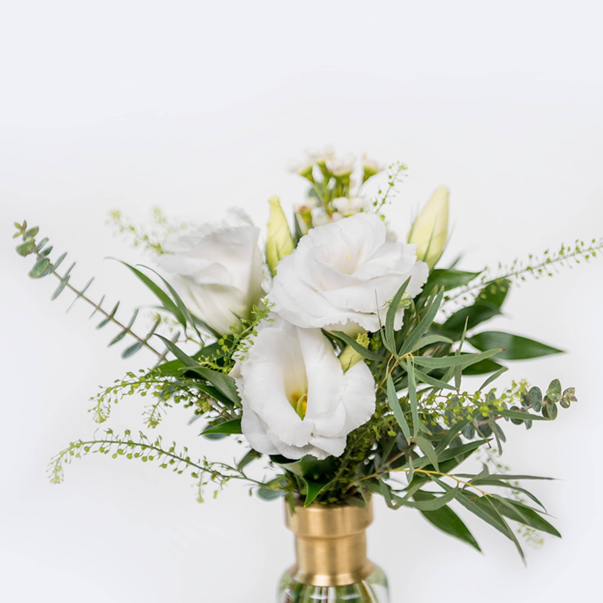 White flowers arranged in a gold vase with green foliage